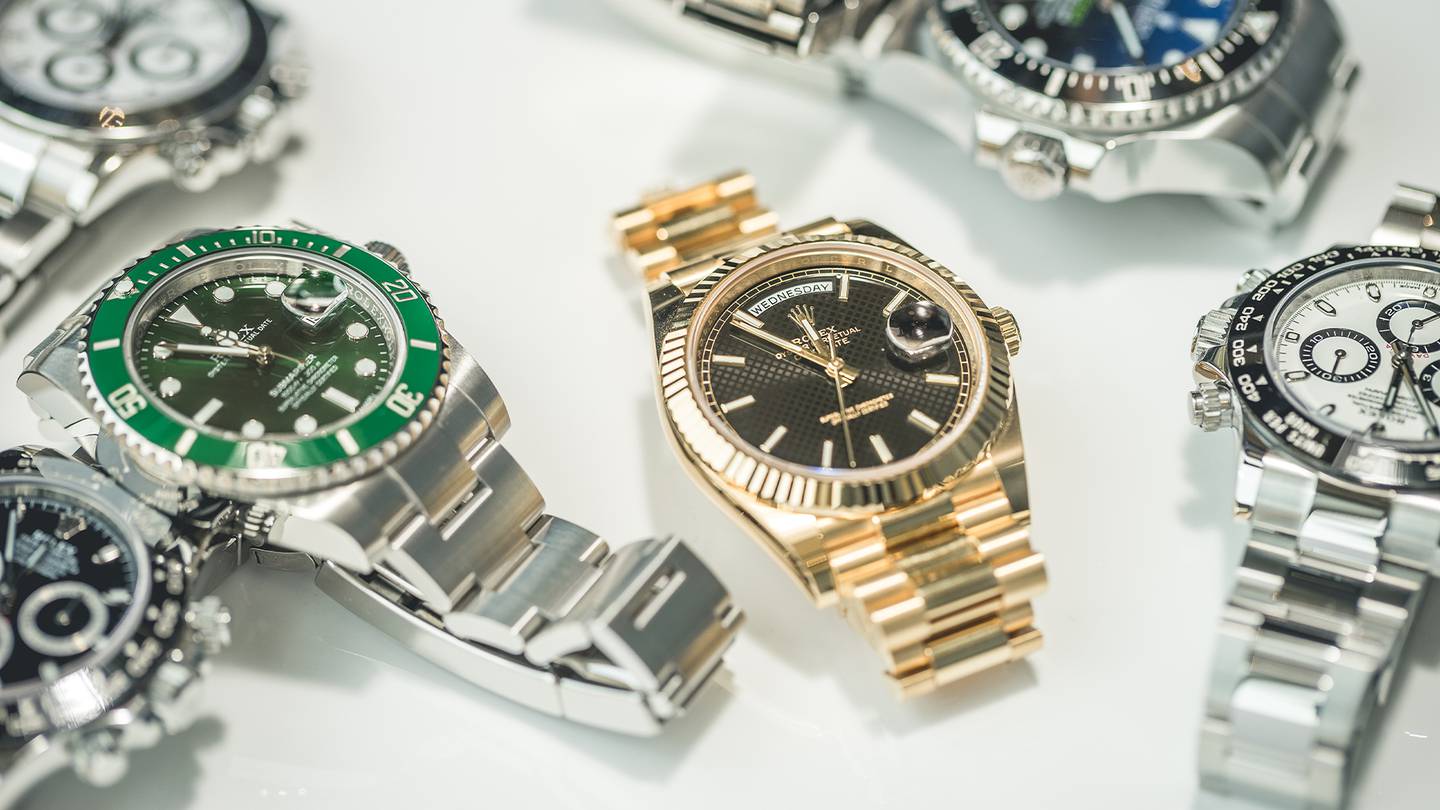 Silver and gold Rolex watches displayed on a white table.
