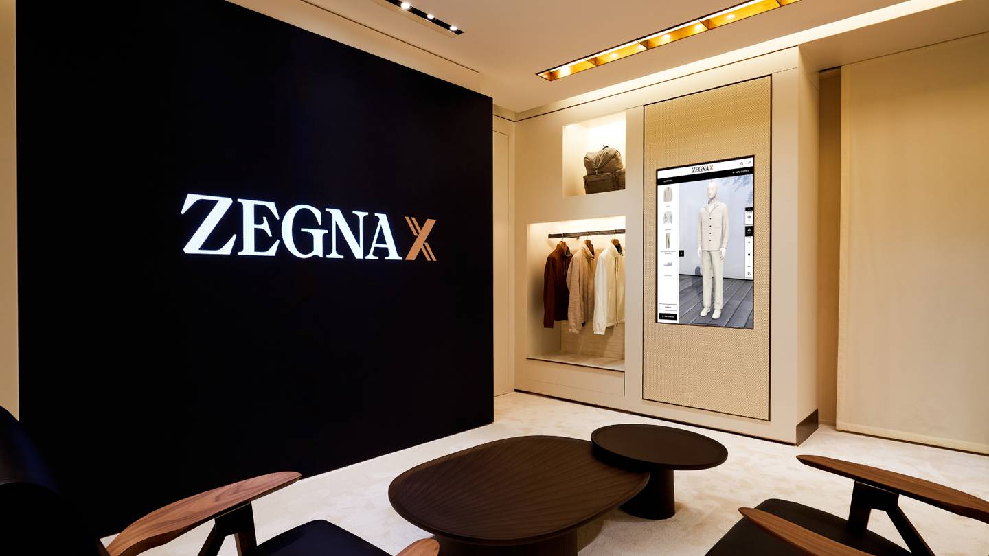 A screen on the wall in a room in Zegna's boutique displays a 3D avatar in a beige jacket and pants.