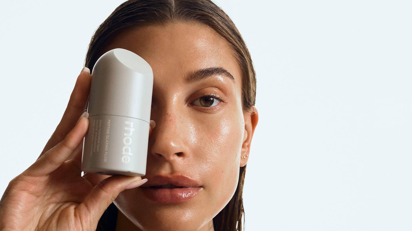 Hailey Bieber holding her new grey Rhode skin care packaging.