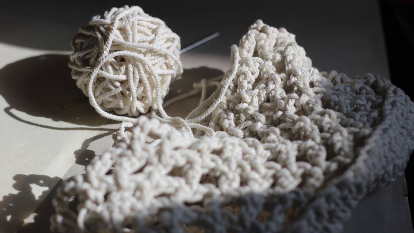 A spool of white wool and half-knitted product.