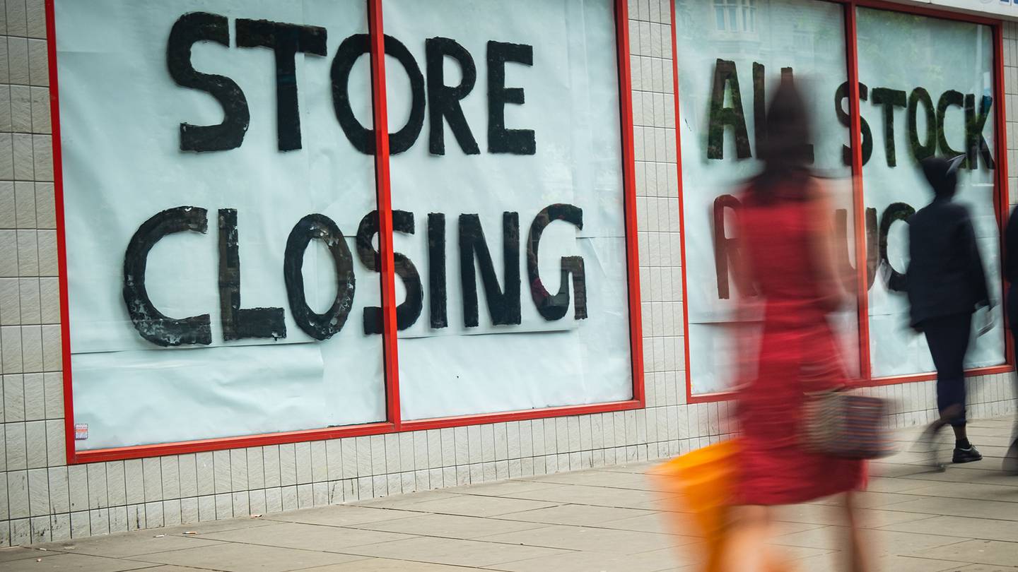 Customers walk past store with "Store Closing" sign in the window.