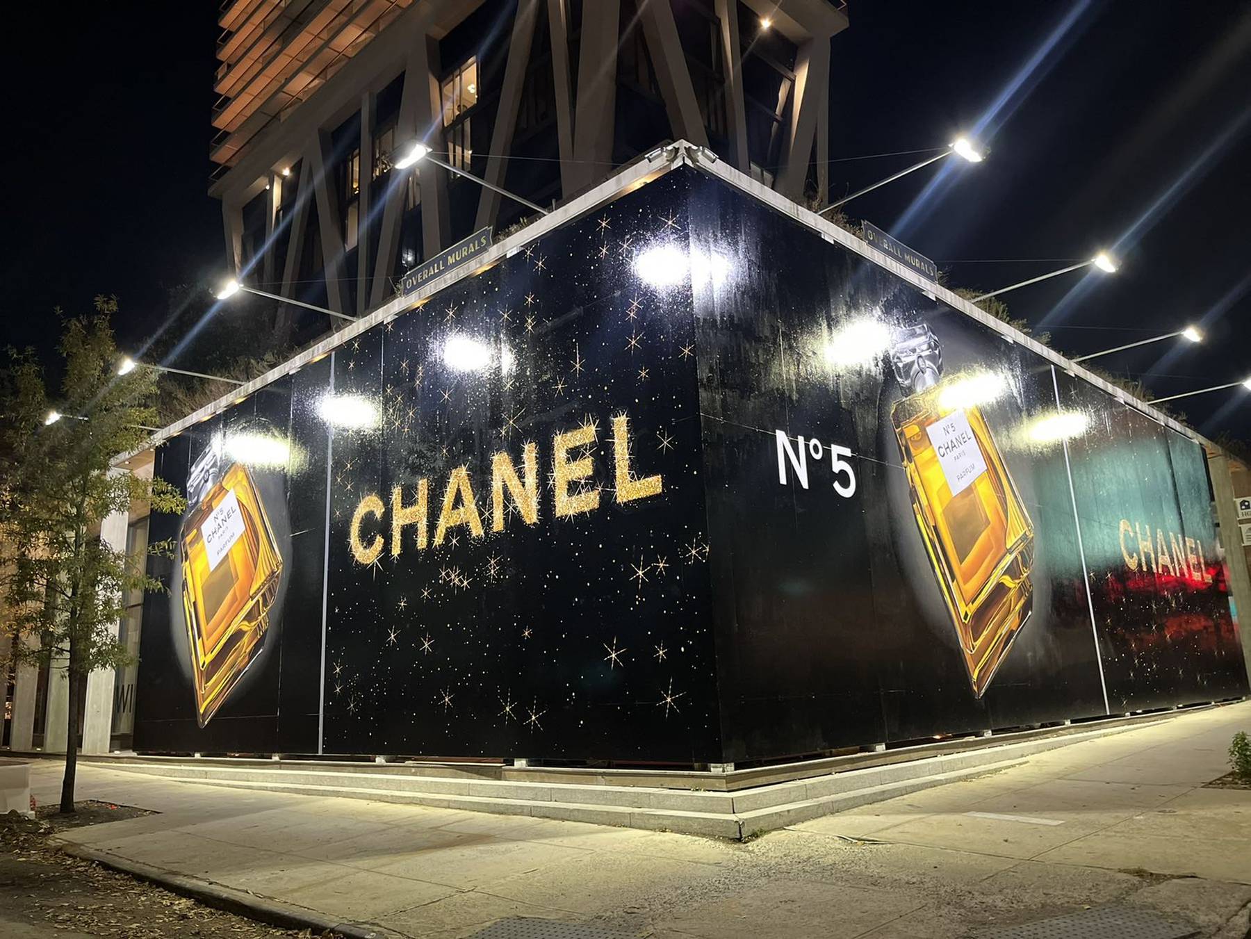 A large advertising billboard for Chanel's No. 5 fragrance at a street corner.
