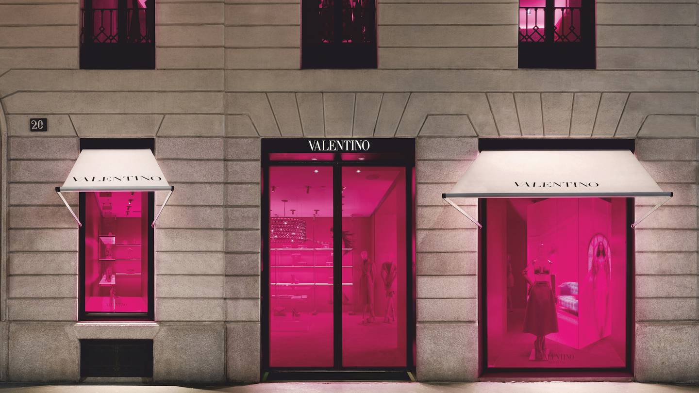 A Valentino storefront with white awning and pink-illuminated windows