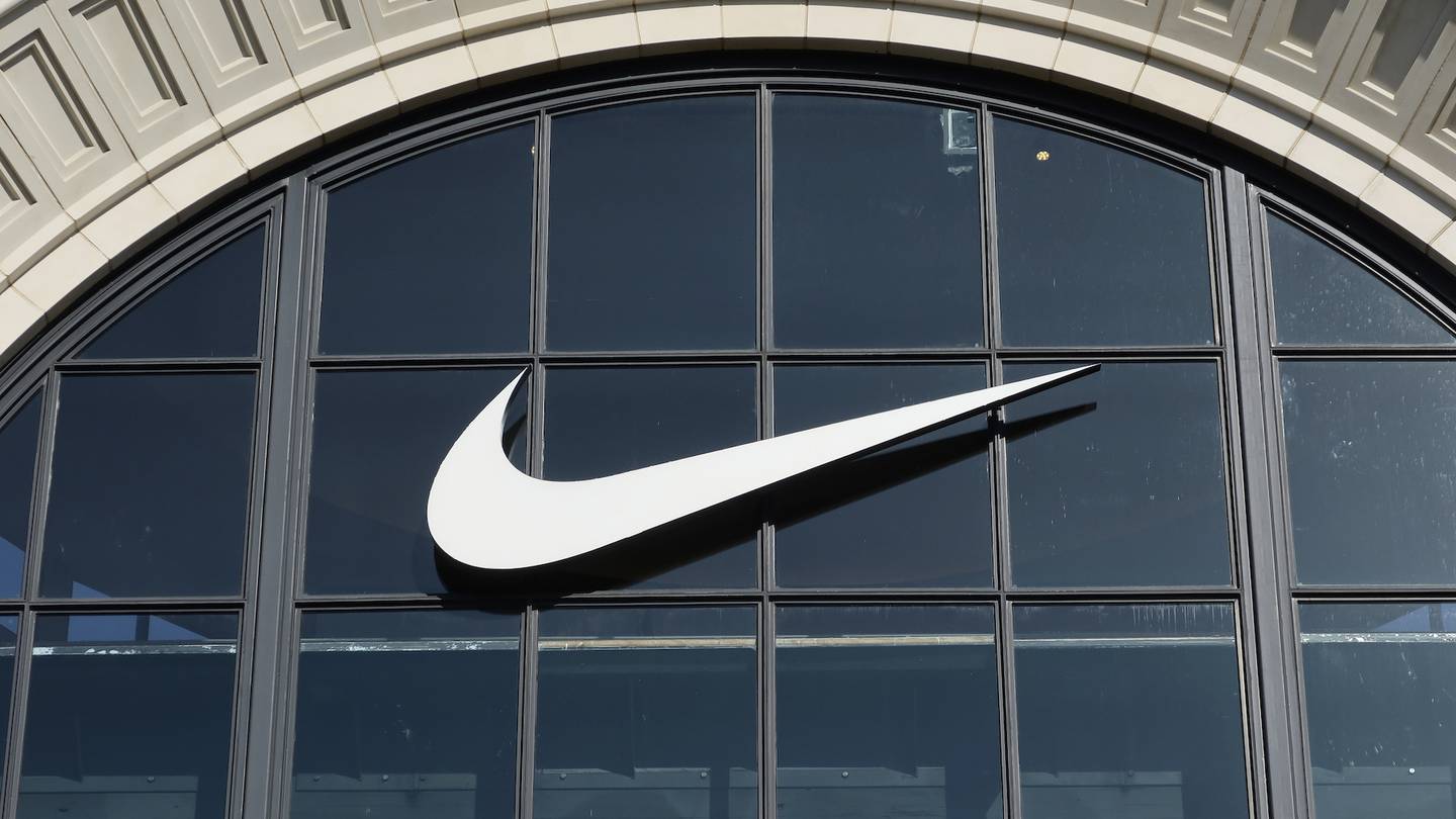 A Nike corporate logo hangs on the front of their store.
