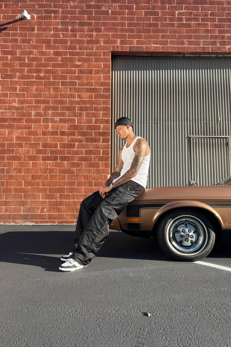 NBA star Kyle Kuzma wearing Spencer Badu's black cargo snow pants. The Canadian-Ghanaian designer's roster of influential stockists has helped to attract several high-profile clients, including K-Pop group NewJeans.