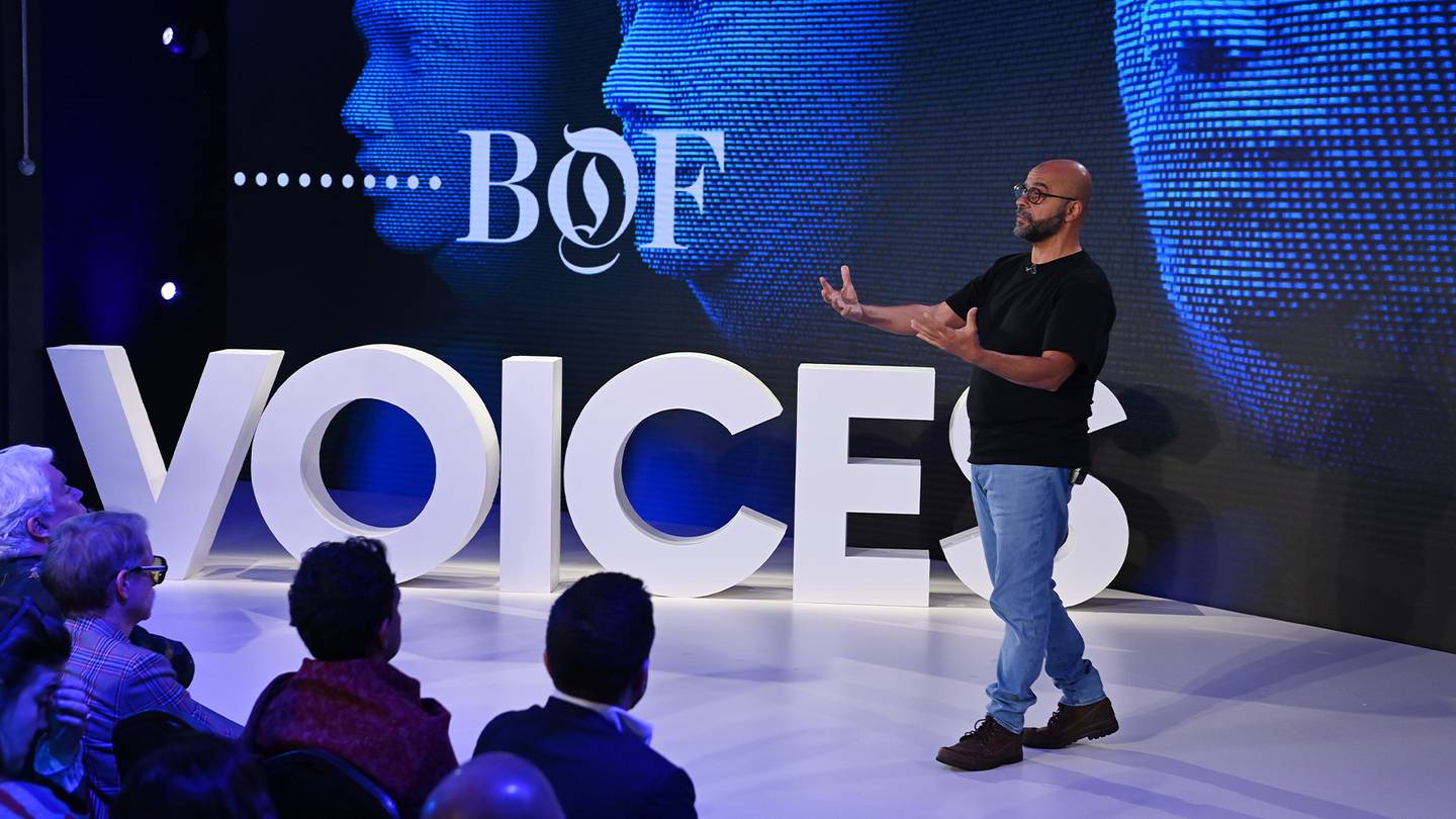 Mo Gawdat standing on stage at VOICES 2022 with the VOICES letters on stage in white in front of a blue background.