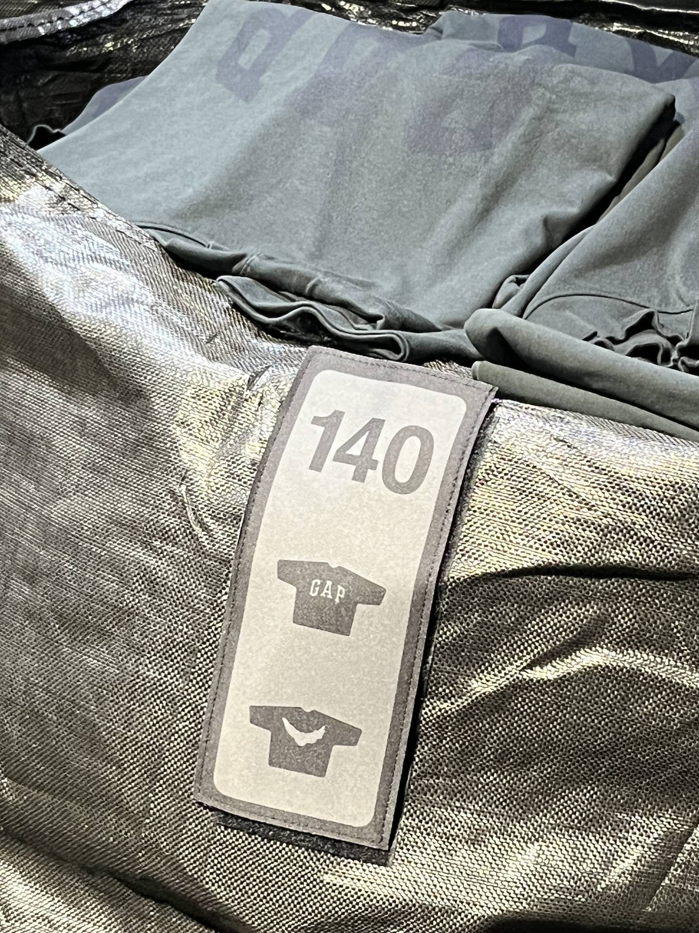 Shirts sit folded in one of the black plastic bags used for the Yeezy Gap experience.