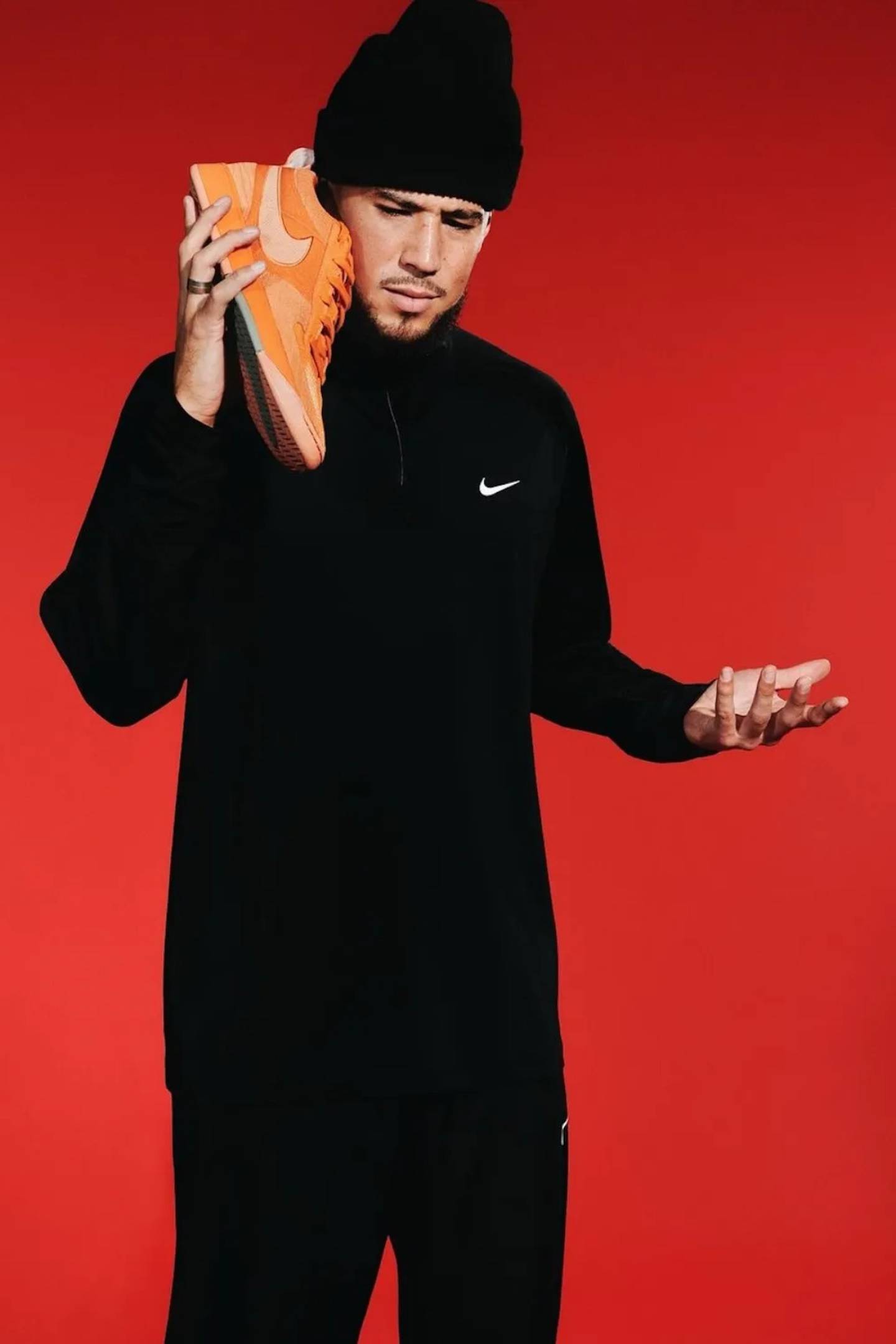 Devin Booker holding his signature Nike shoe