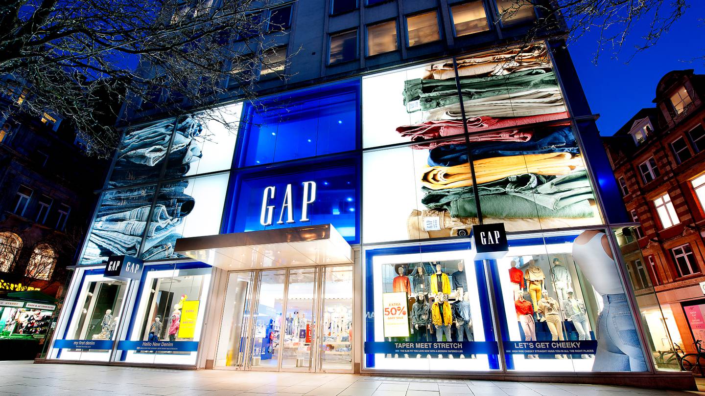 The exterior of a Gap store brightly lit against a darkening sky.
