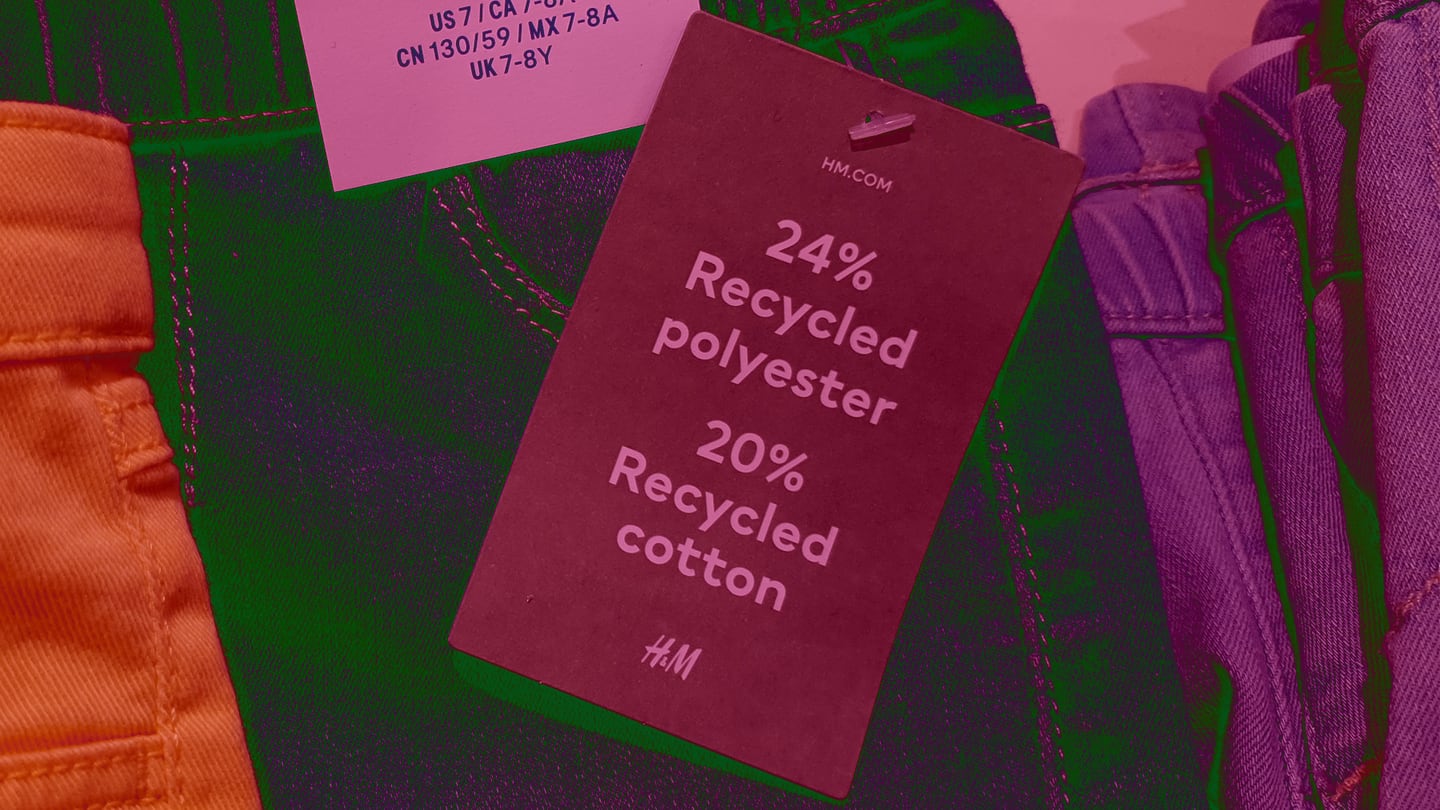 An H&M clothing tag attached to a pair of jeans that says "24 precent recycled polyester / 20 percent recycled cotton.