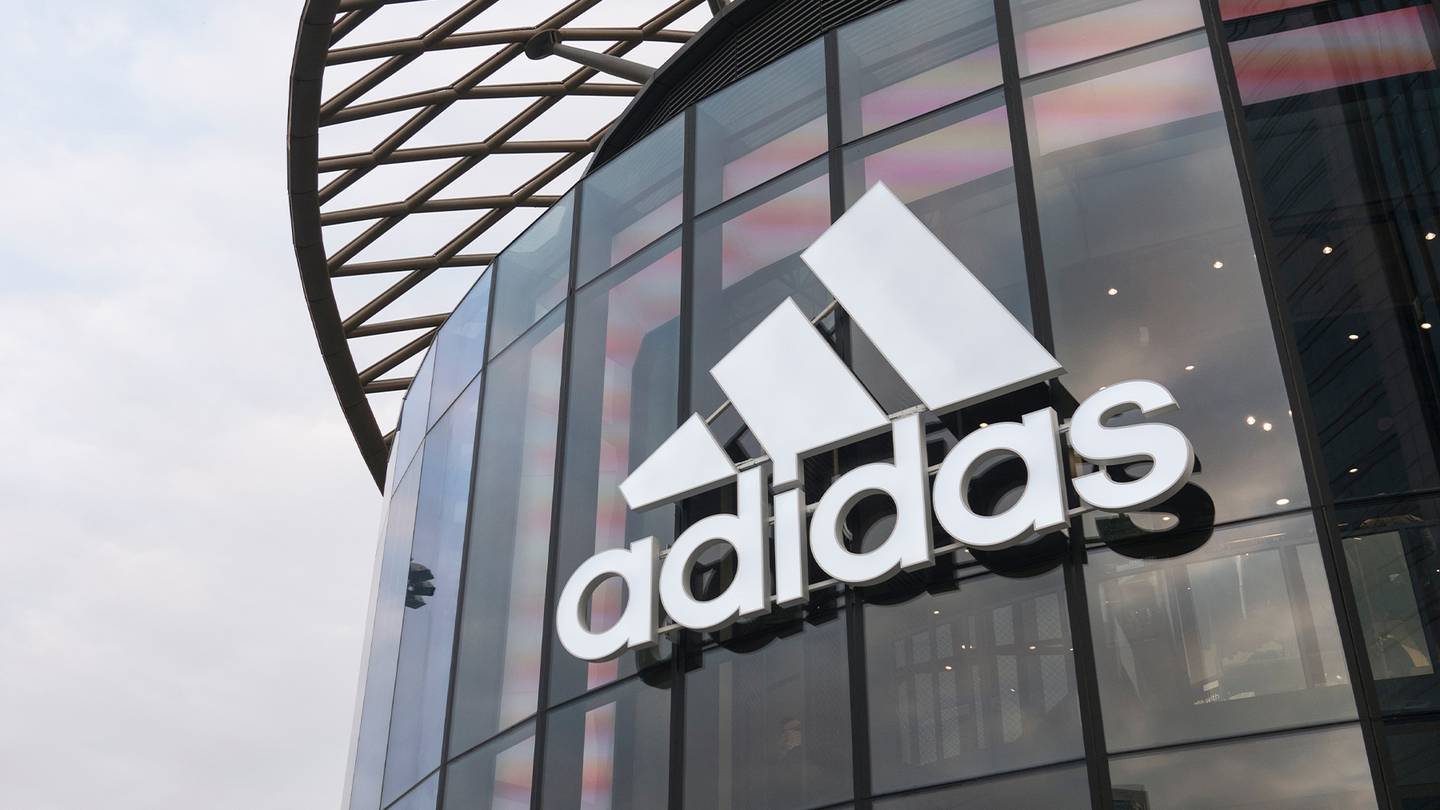 A shot of the Adidas logo on a glass storefront.