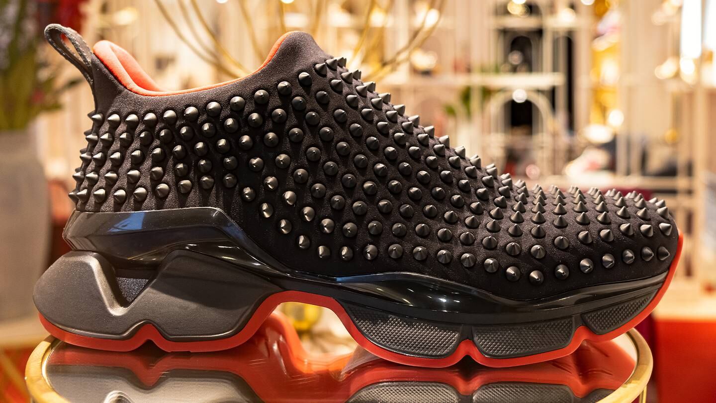 Louboutin studded black sneaker with a red shoe sole.
