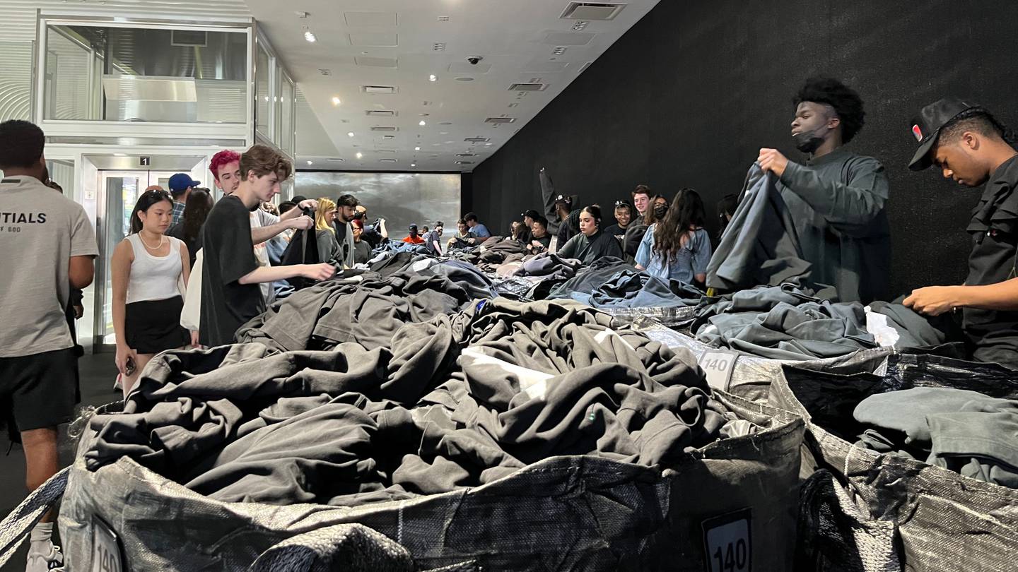 Shoppers sift through black plastic bags filled with Yeezy Gap clothing.