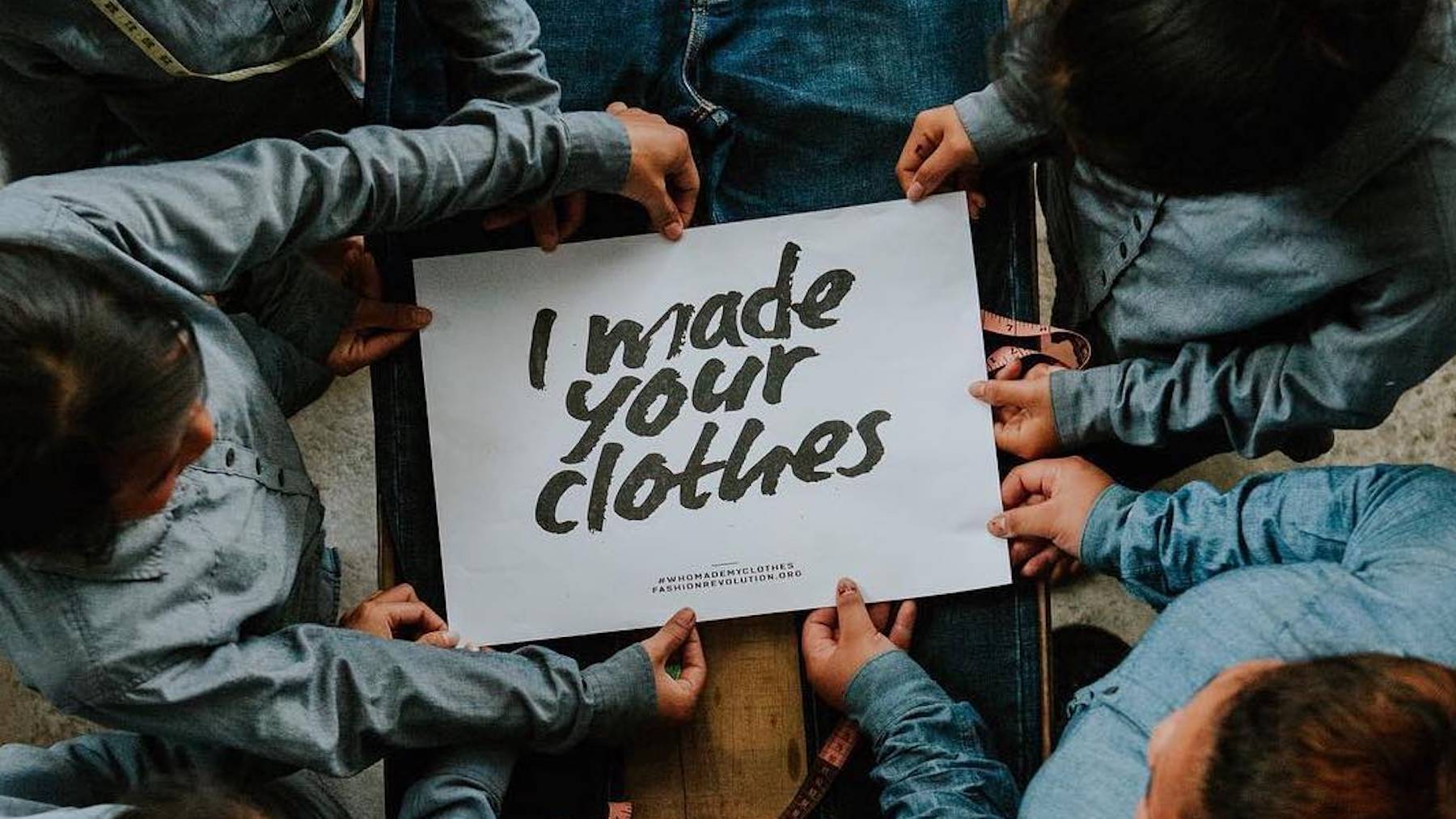 A group of denim garment-makers hold a sign saying "I made your clothes."
