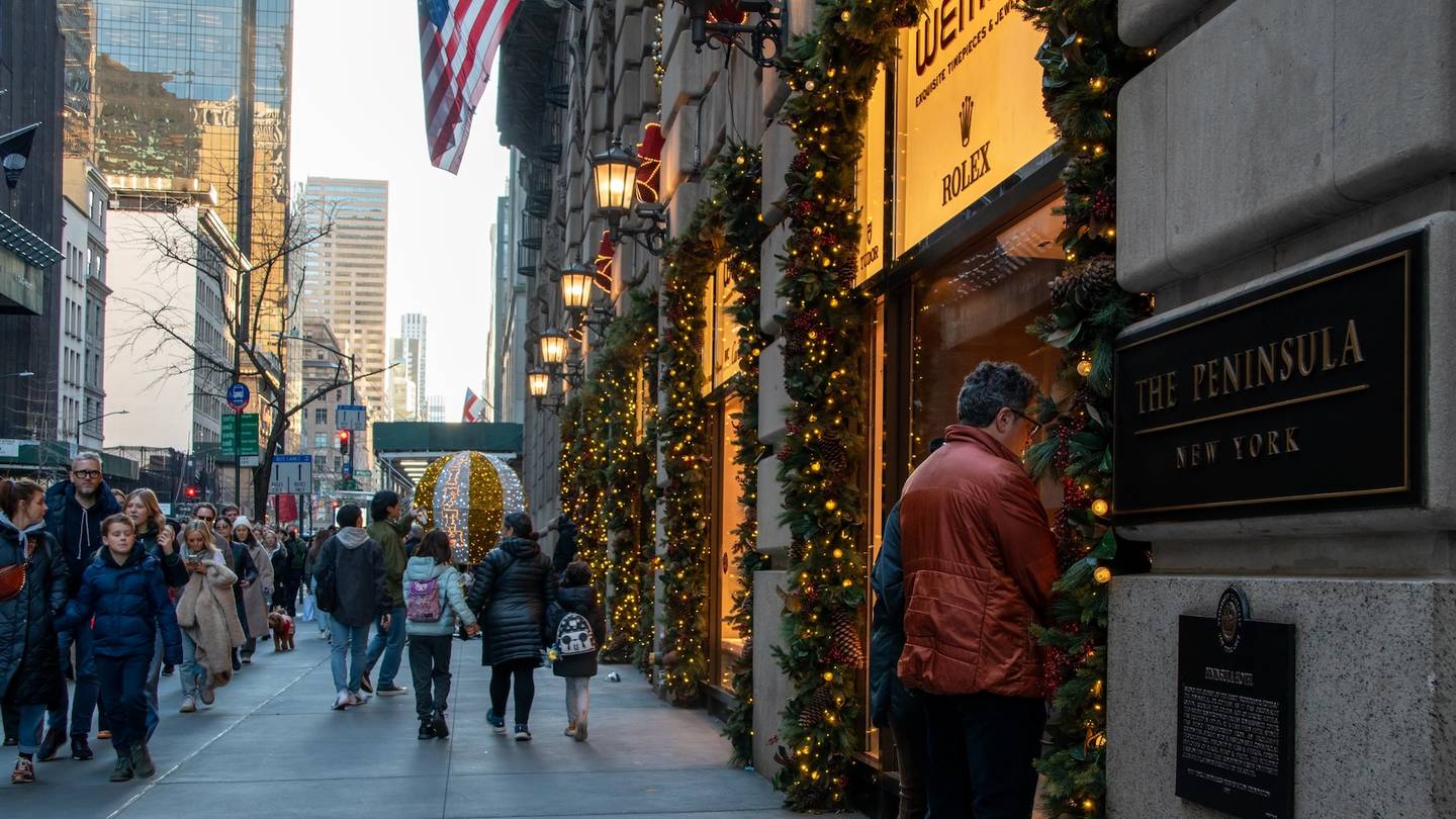 Shoppers look in store windows and walk down the street on Fifth Avenue in New York during the holiday season.
