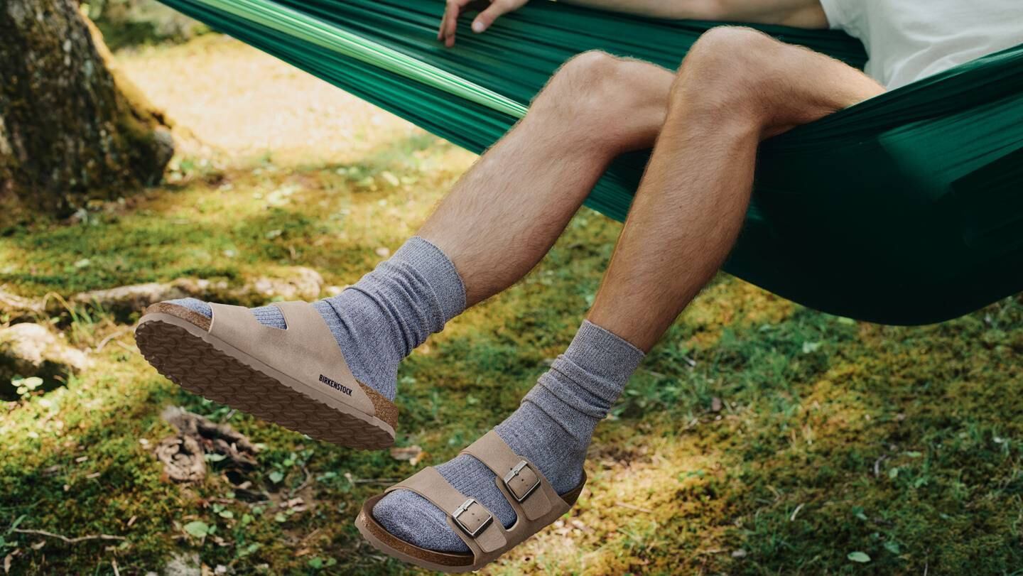 Man wearing Birkenstock sandals in hammock.