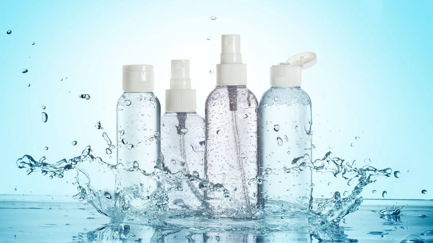 Beauty products in clear bottles in a blue background with a water splash.