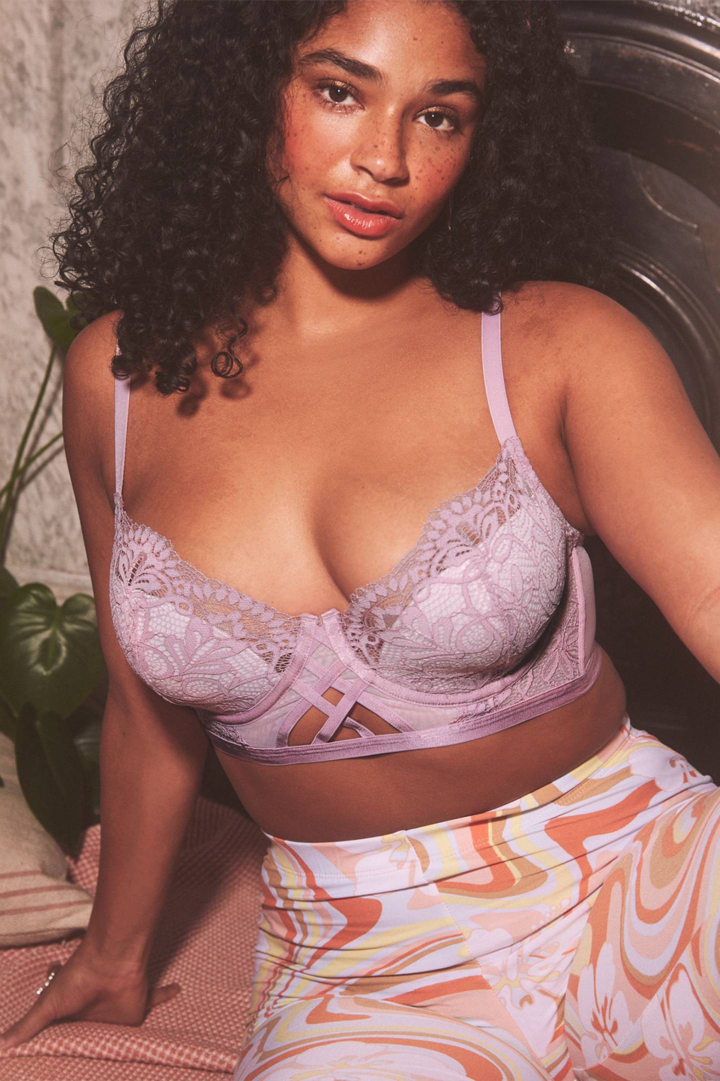 A model wears a lilac lace detailed bra with wave patterned leggings for an Adore Me campaign.
