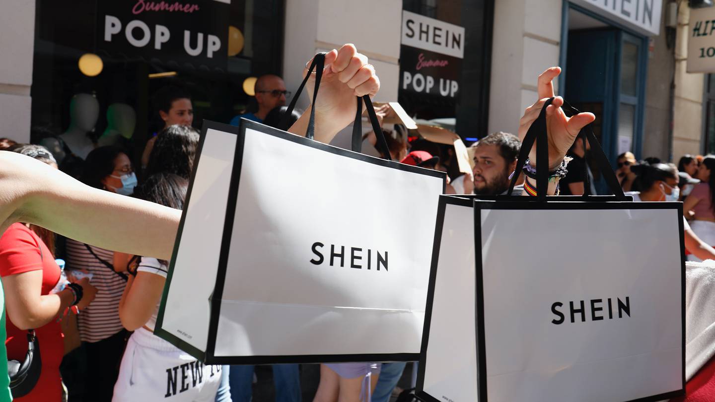 Shoppers hold a loft Shein shopping bags outside a pop-up store.