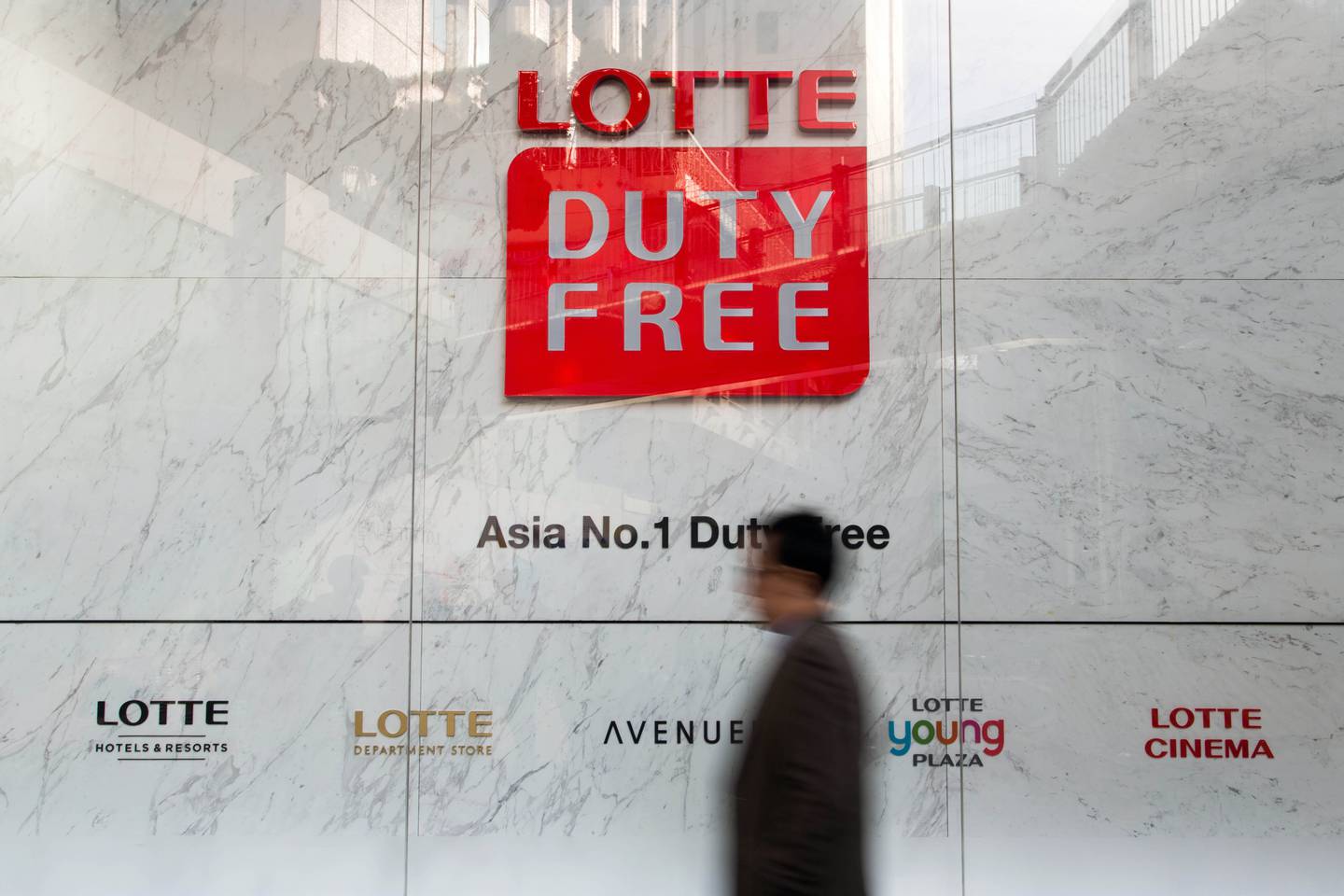 A man walks past signage for a Hotel Lotte Co. Duty Free store in Seoul, South Korea.