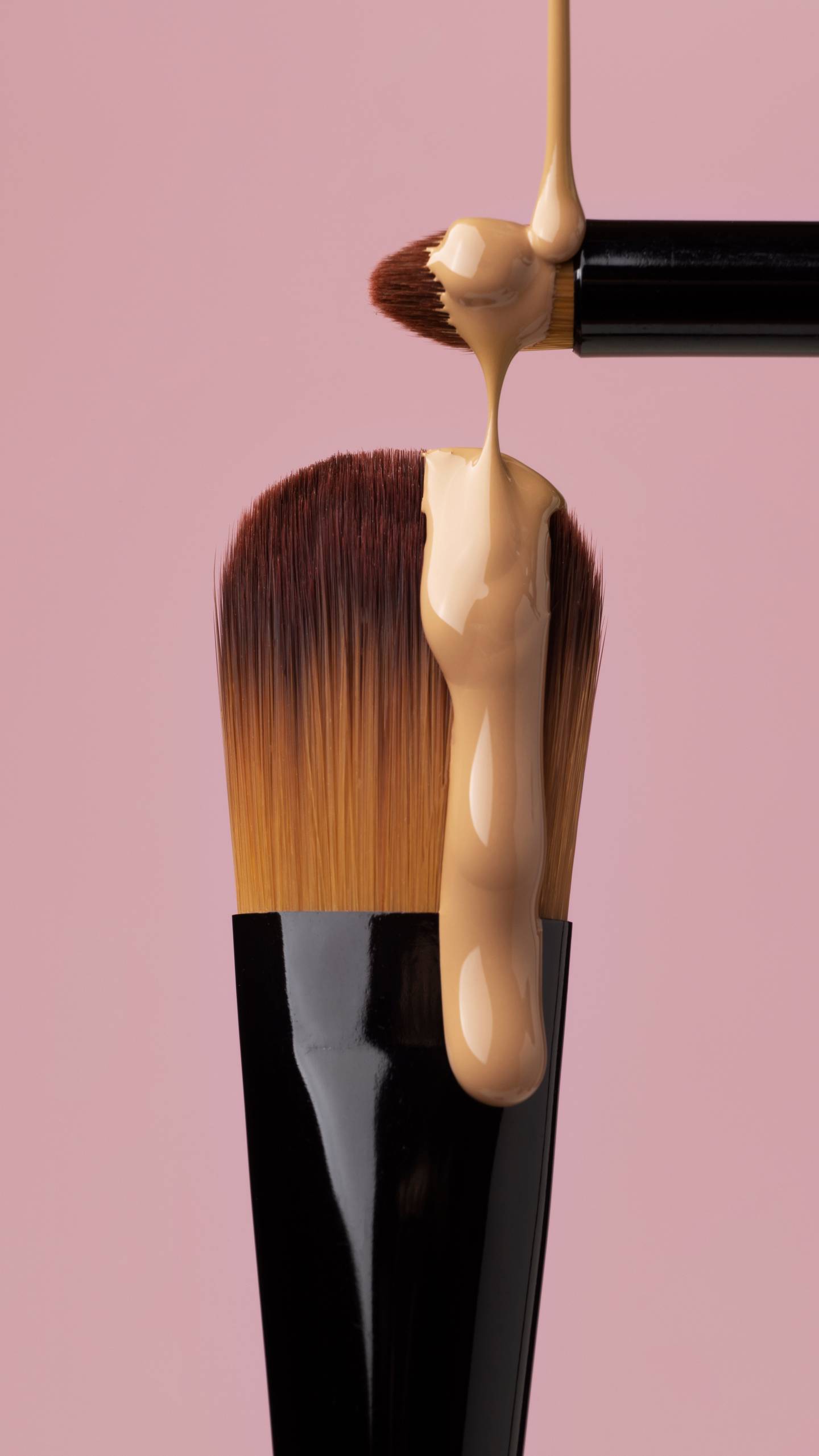 An image of foundation dripping down a makeup brush.
