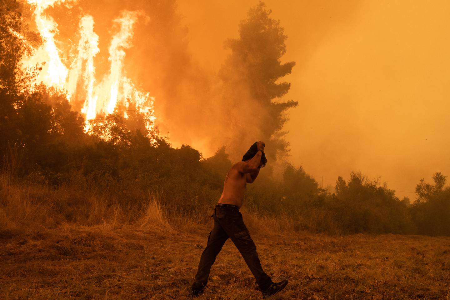 A resident shields himself from the heat of a forest wildfire in Pefki on Evia island, Greece, on August 8, 2021.