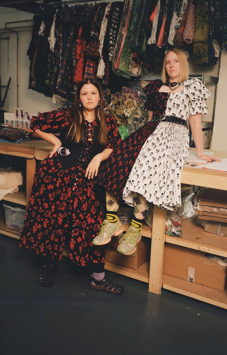 In their studio, Emma Chopova stands on the left, leaning on a counter top, and Laura Lowena sits on counter on the right.