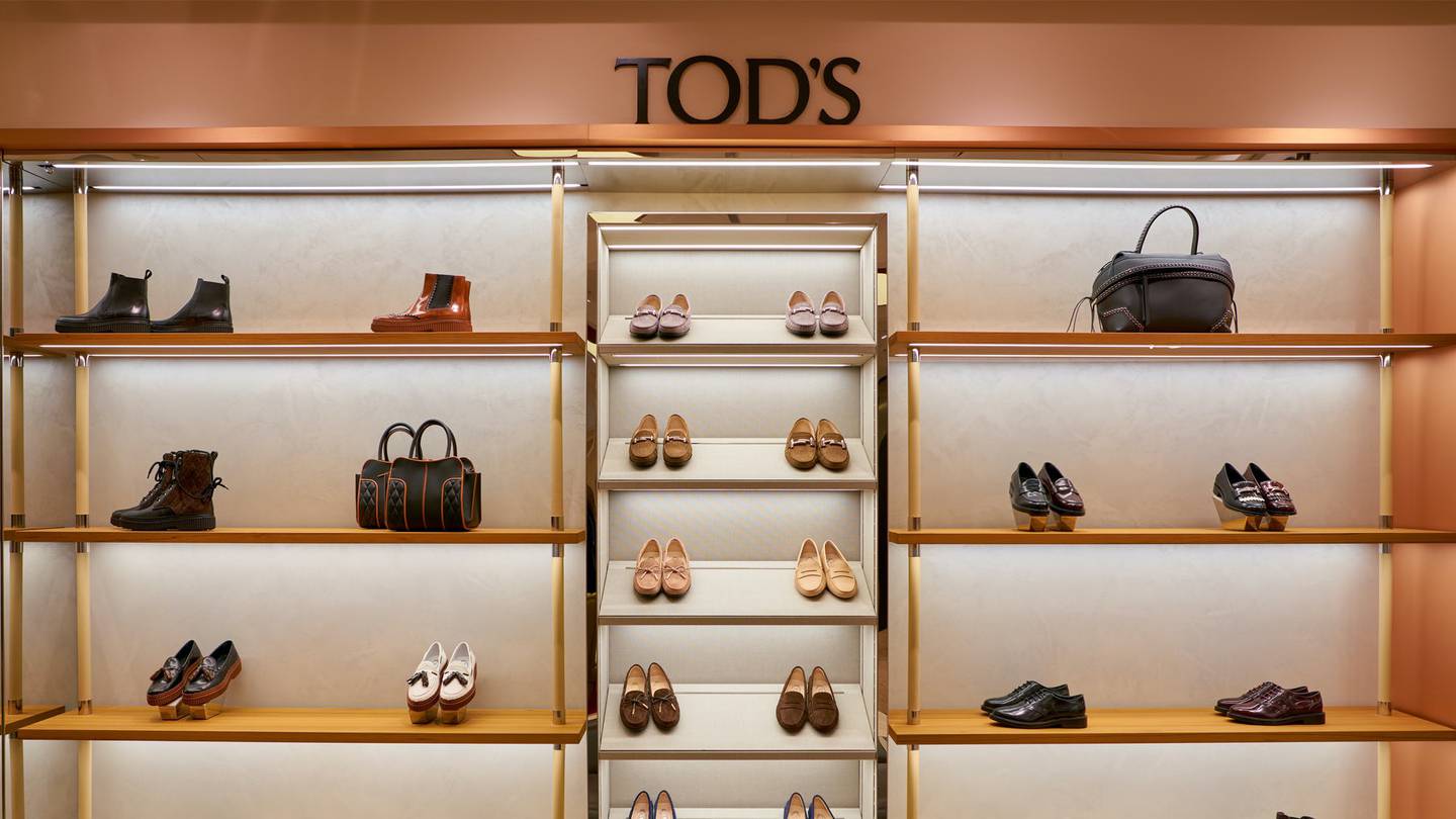 The interior of a Tod's store with shelving lined with leather shoes and handbags.