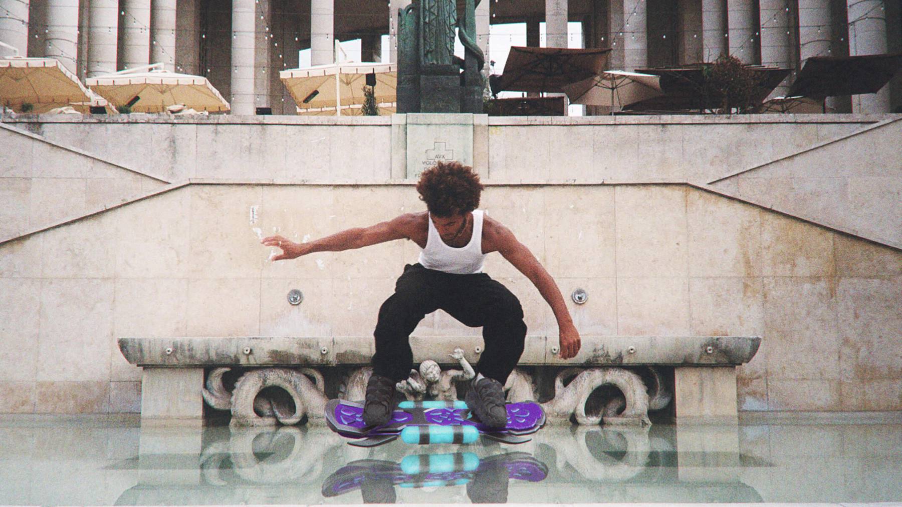 A guy skates by a building on a floating digital skateboard.