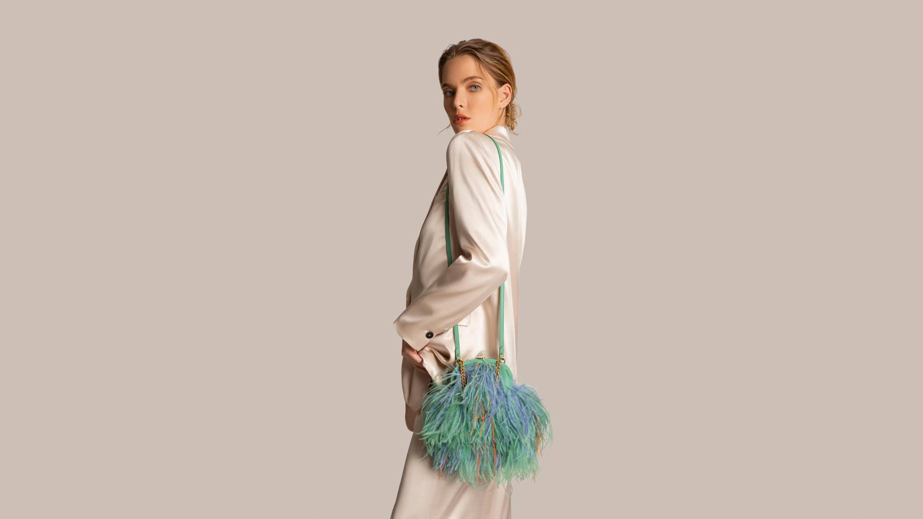 Woman in white satin suit wearing ostrich feather evening bag.