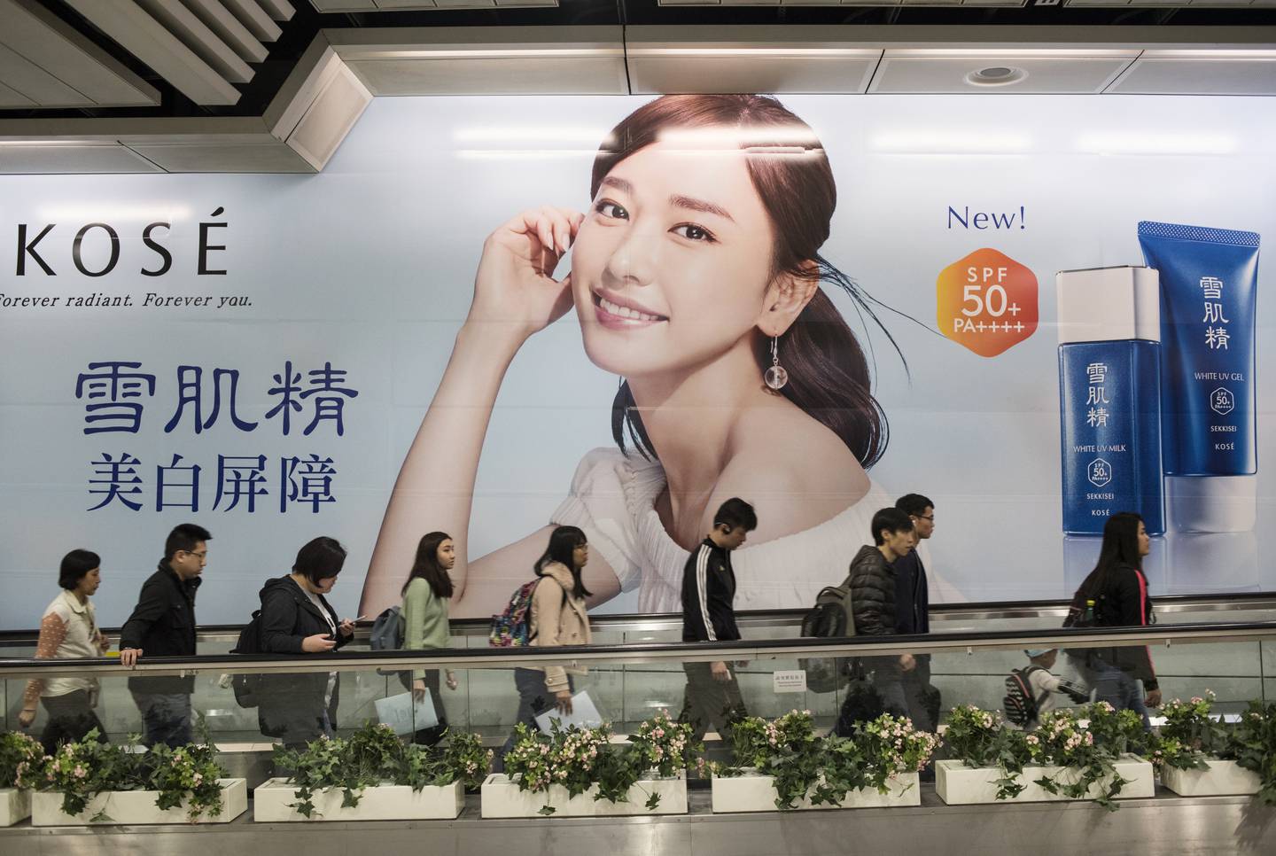 Commuters at Hong Kong's MTR station pass by a large advertising of cosmetic and skin care Sekkisei.