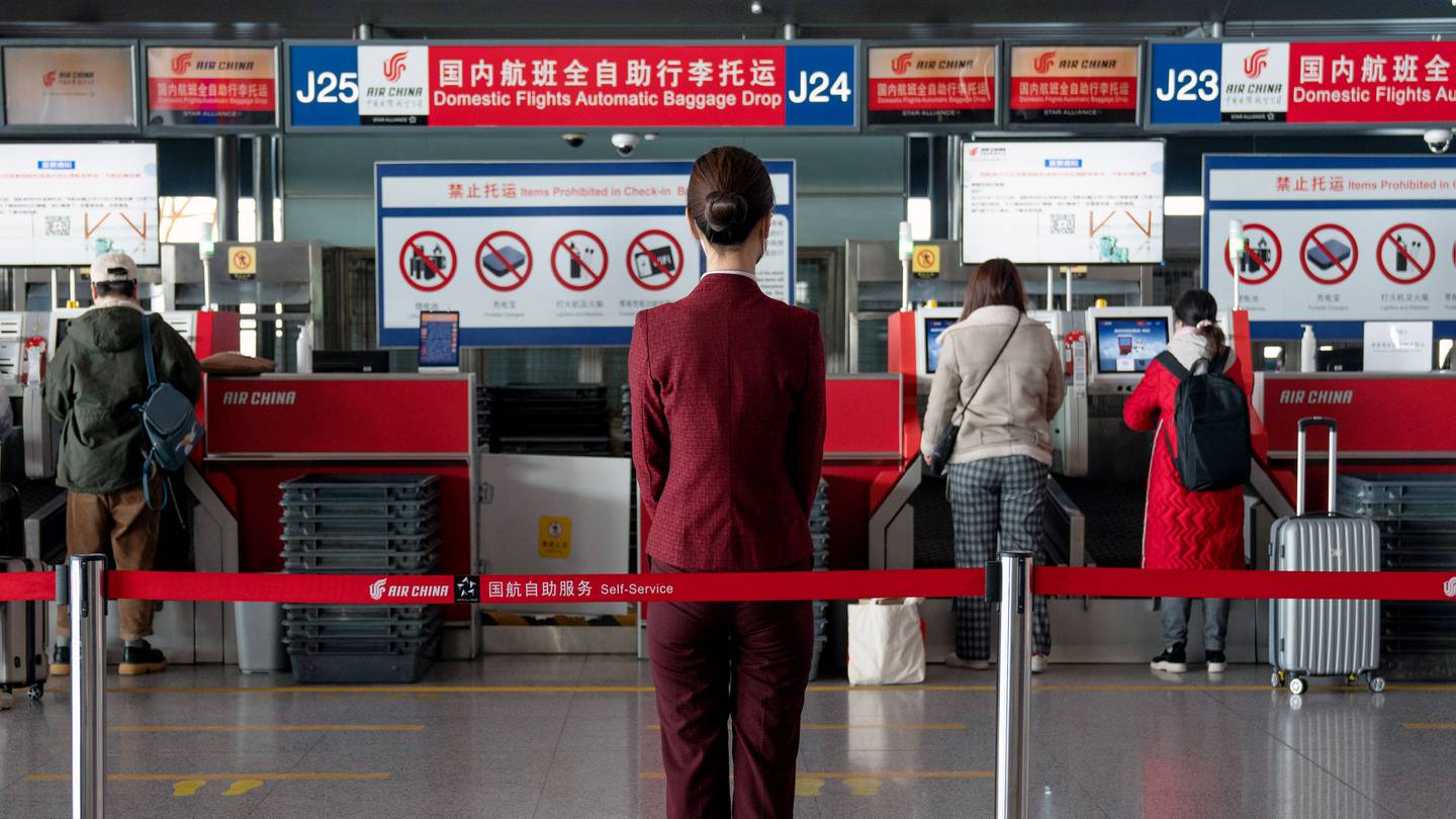 A staff stands in front of Air China Ltd. baggage drop counters for domestic flights at Beijing Capital International Airport ahead of Lunar New Year.