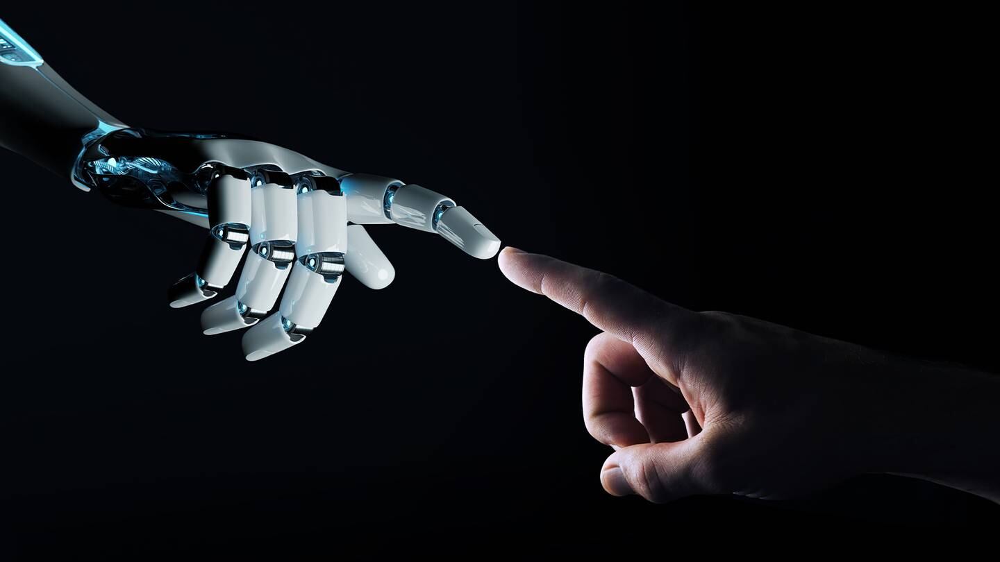 A robot hand and human hand reaching out to touch fingers.