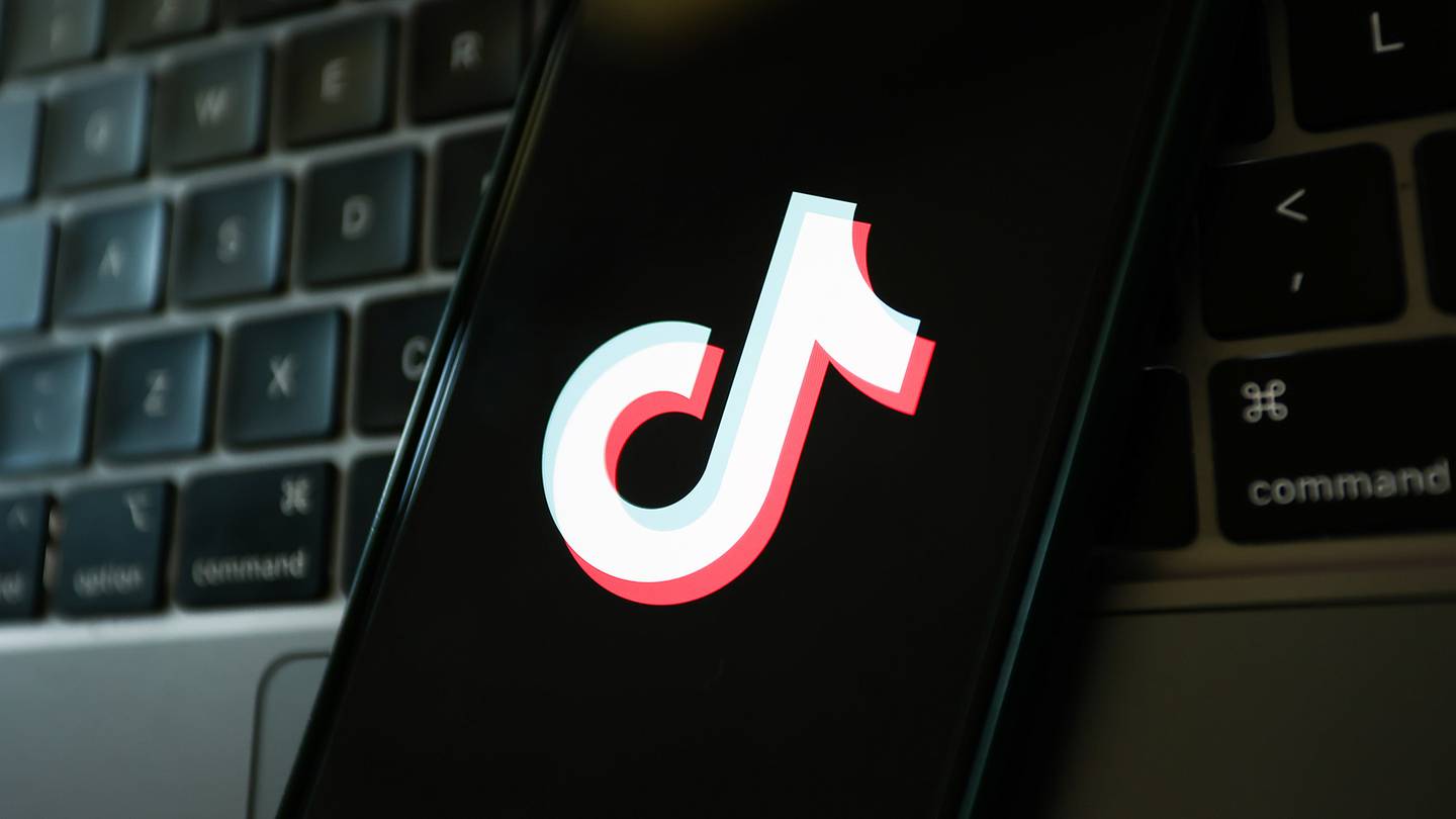 A laptop keyboard and TikTok logo displayed on a phone screen.