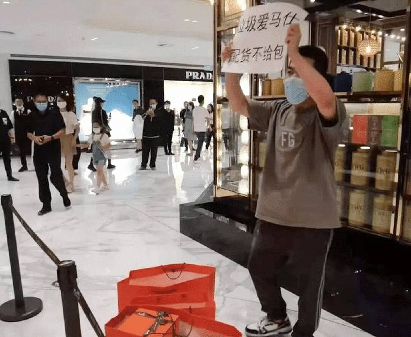 A lone protestor holds a sign saying “Rubbish Hermès peihuo but no bag”.