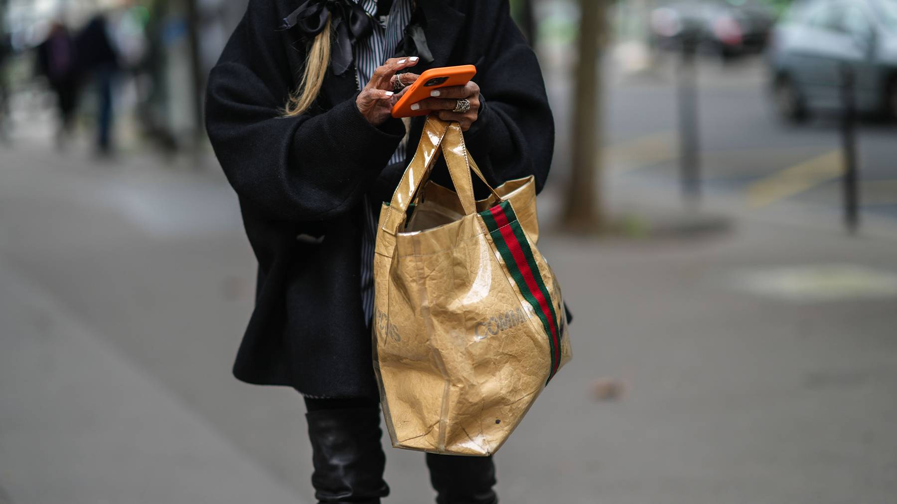 Person carrying a Gucci bag while texting.