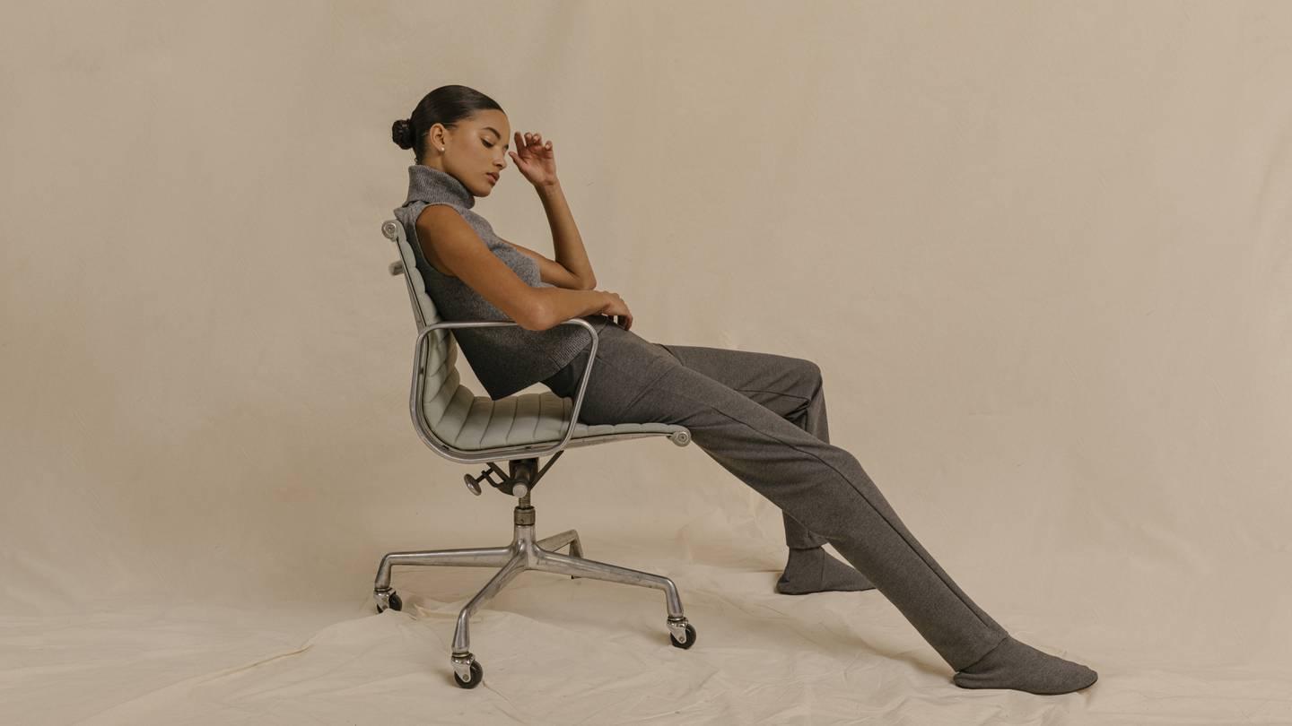 Model in office chair wearing grey top and grey pants by Leset.