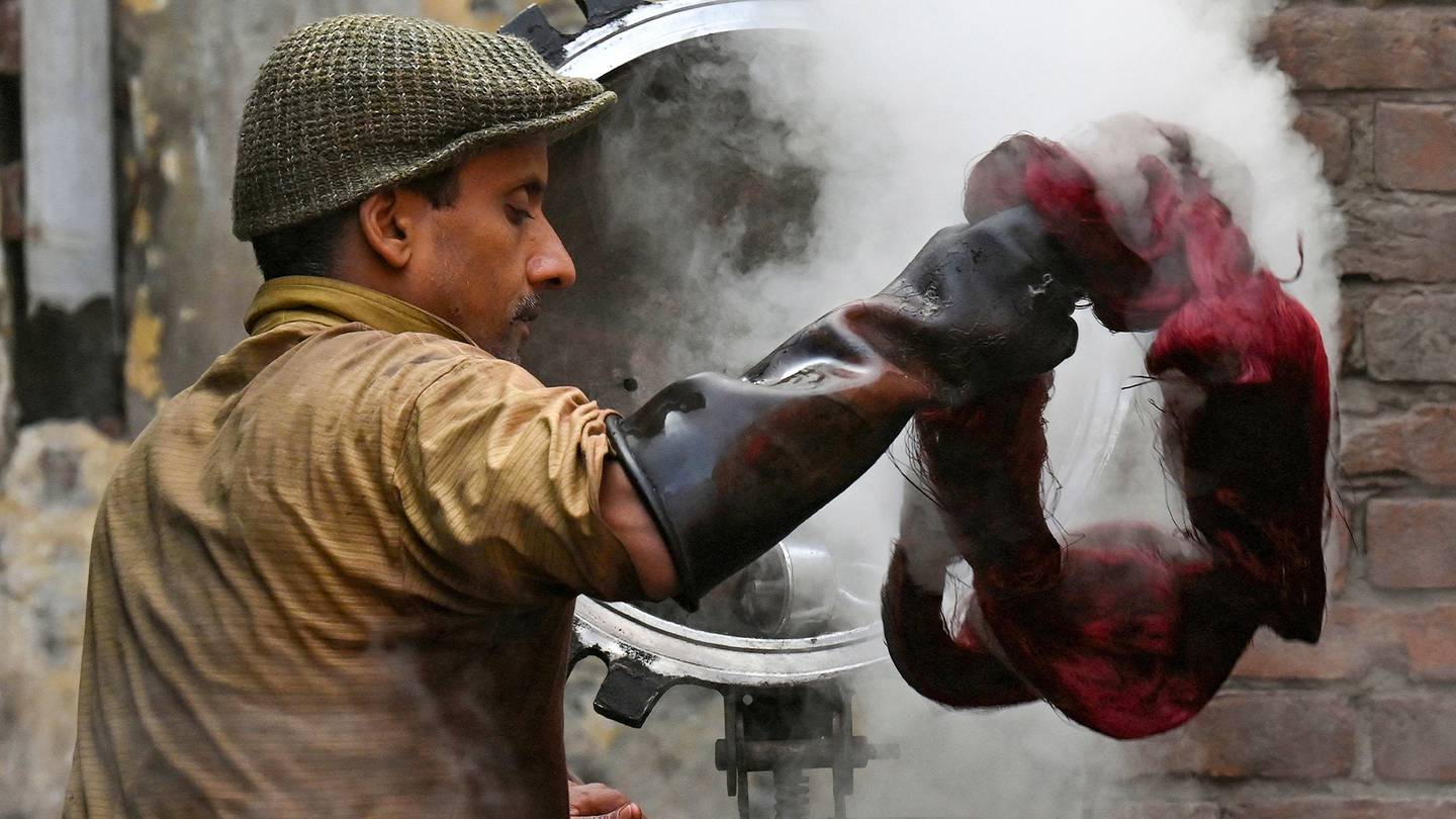 A worker stands in front of steaming machinery as he dyes thread at a factory in Lahore, Pakistan.