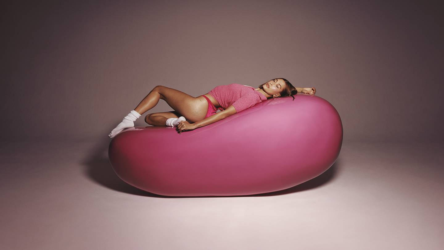 A woman lying on a life size jellybean.