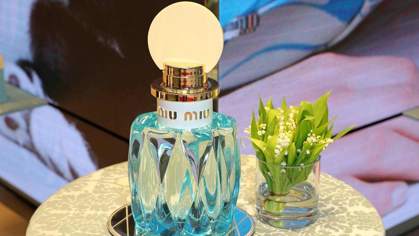 A blue bottle of Miu Miu perfume sits on a table.