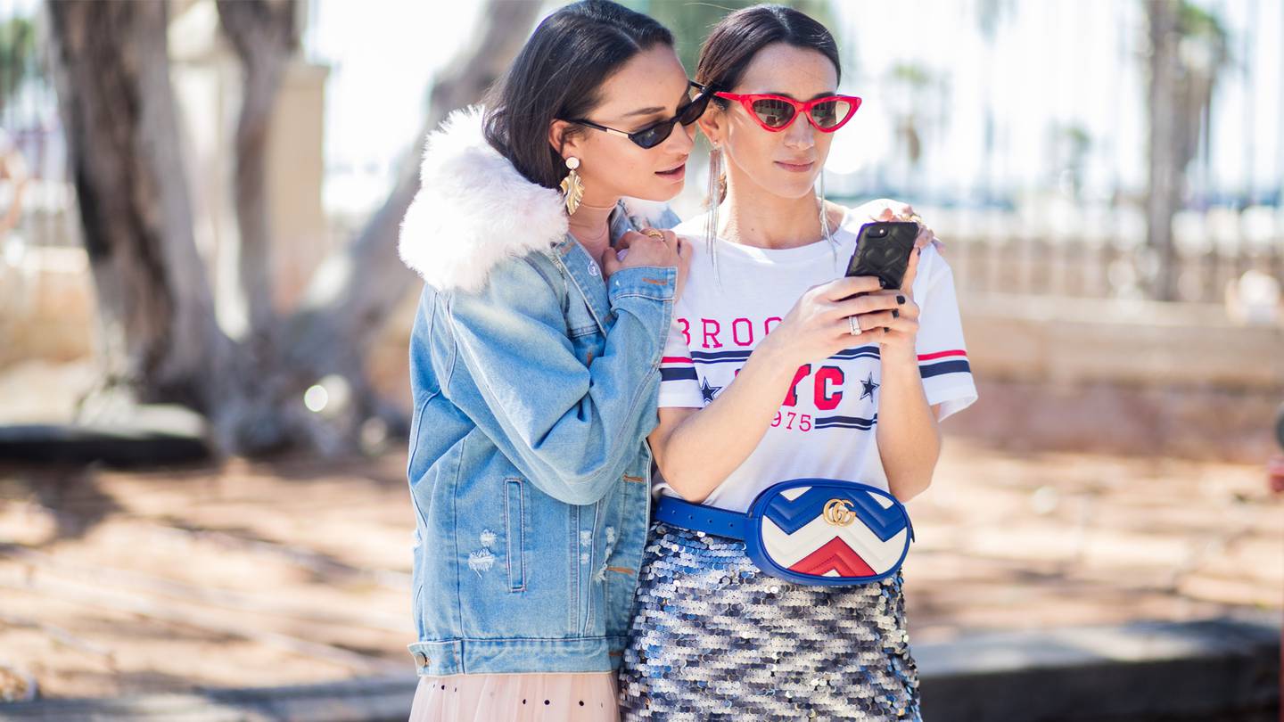 two women fashion looking at phone