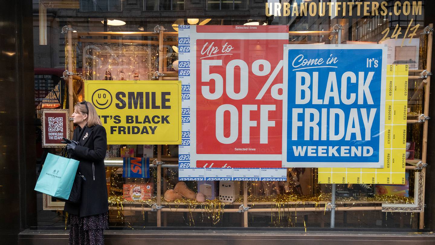 Woman stands in front of Urban Outfitters store during Black Friday.