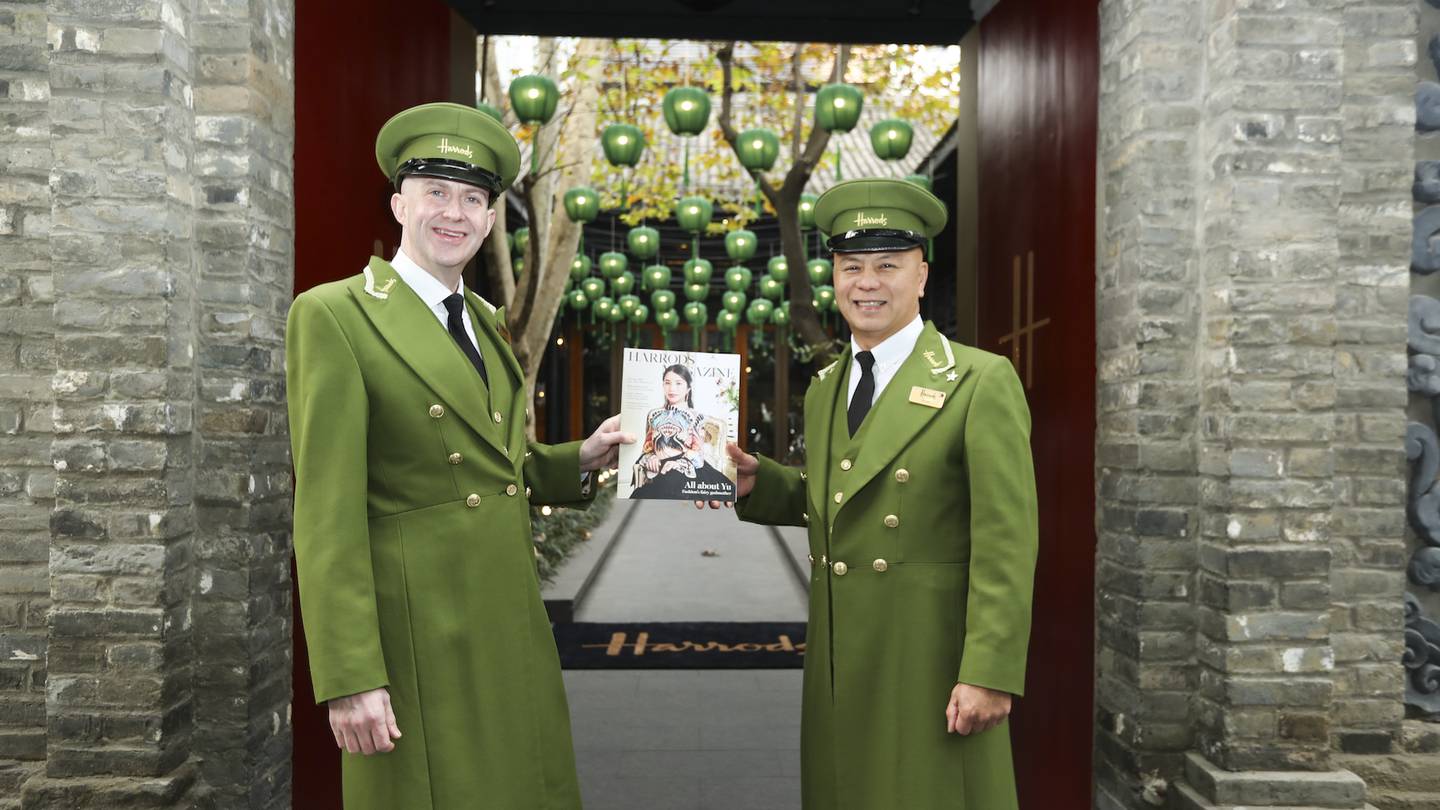 Two men dressed in green Harrods uniforms stand at the entrance of a Harrods opening held in Chengdu in 2019.