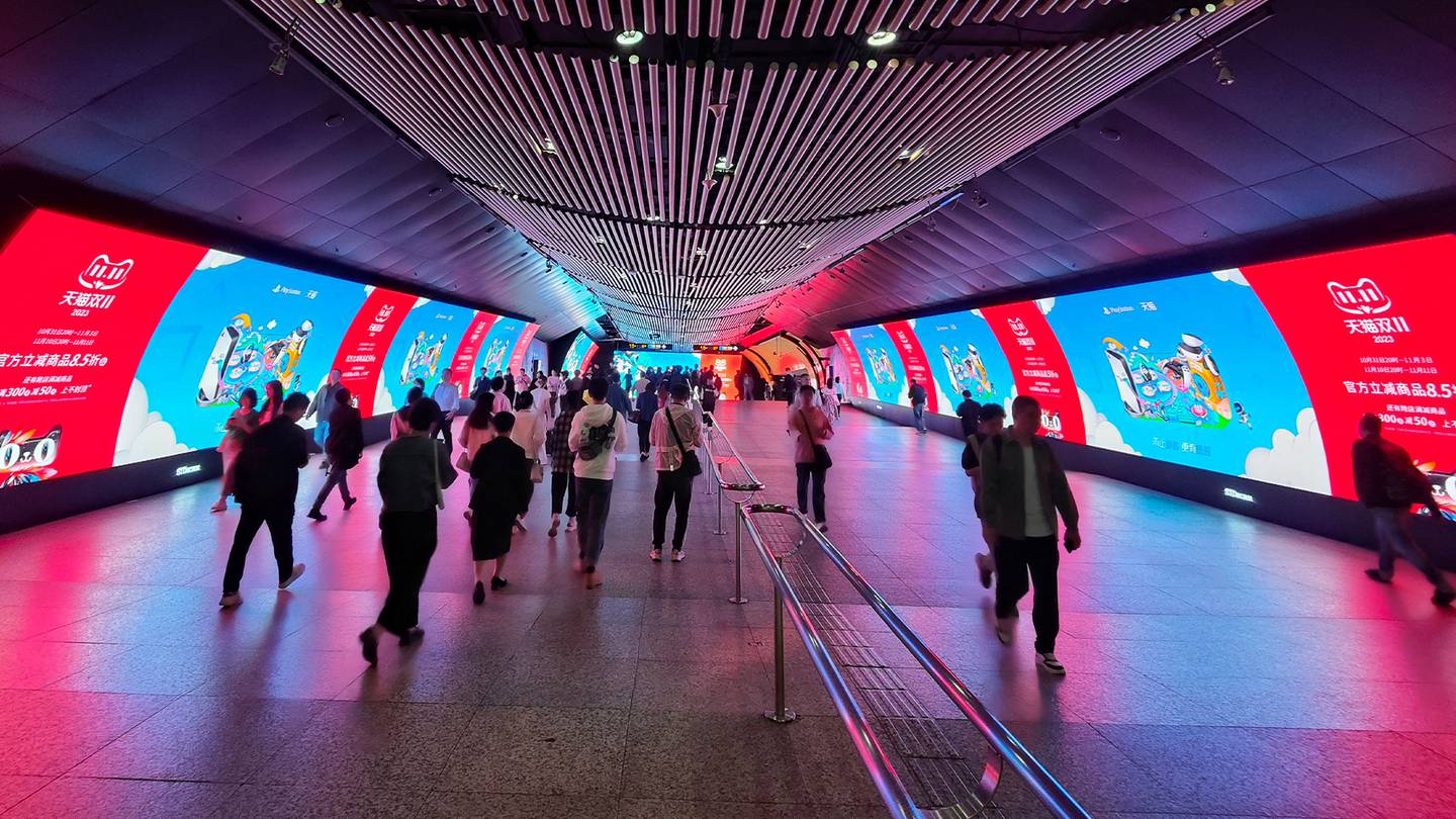 Citizens pass by the Double 11 shopping carnival promotional LCD screen displayed in a subway in Shanghai.