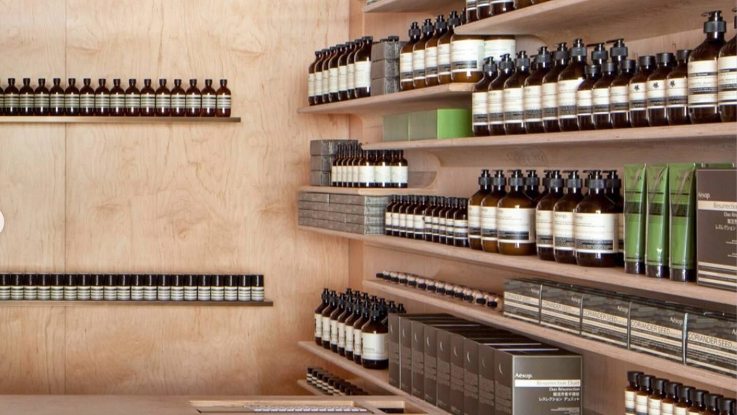 Interior of an Aesop store with products lining the stone and wood shelving.