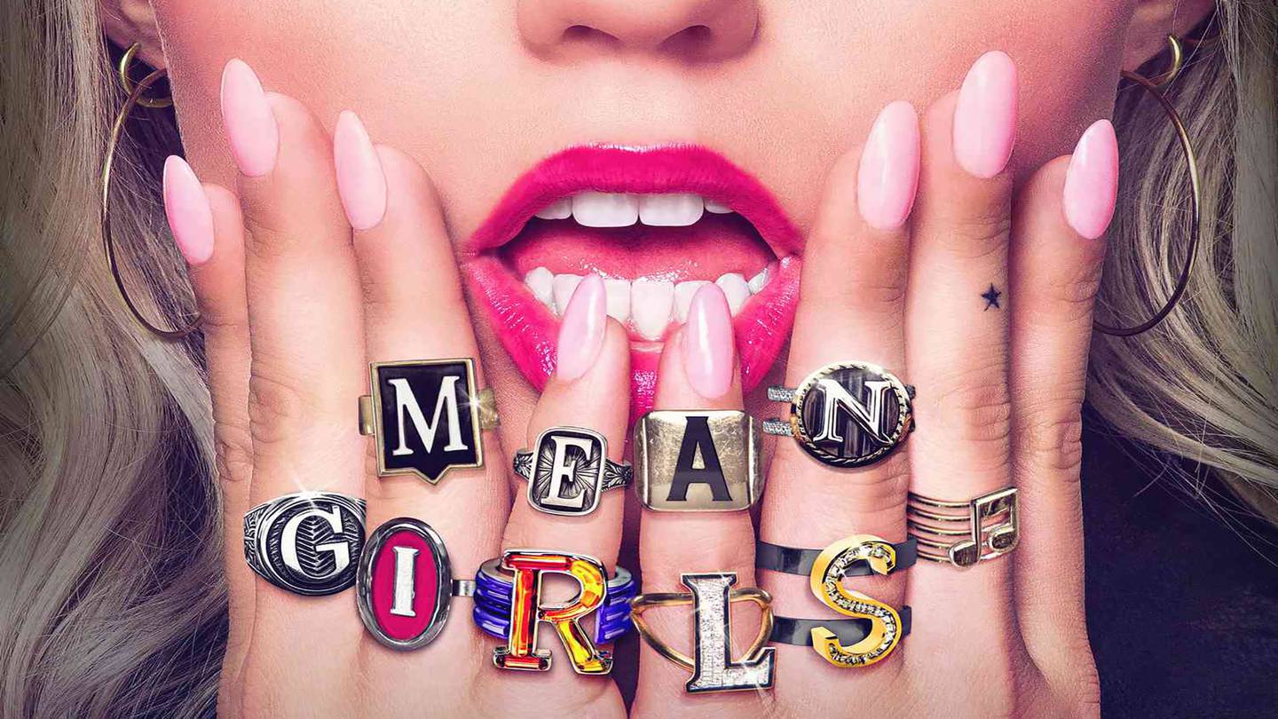 A women's lower face. She is wearing bright pink lipstick and has ring that read "mean girls."