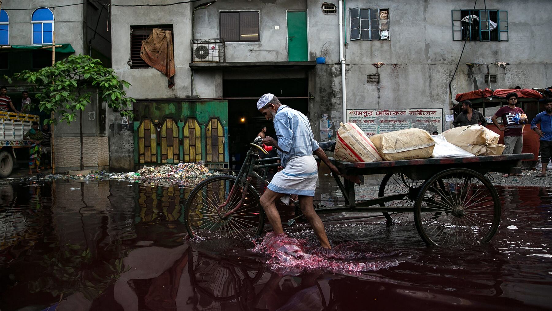 A man walks through rain and dye outside a dyeing factory in Bangladesh.