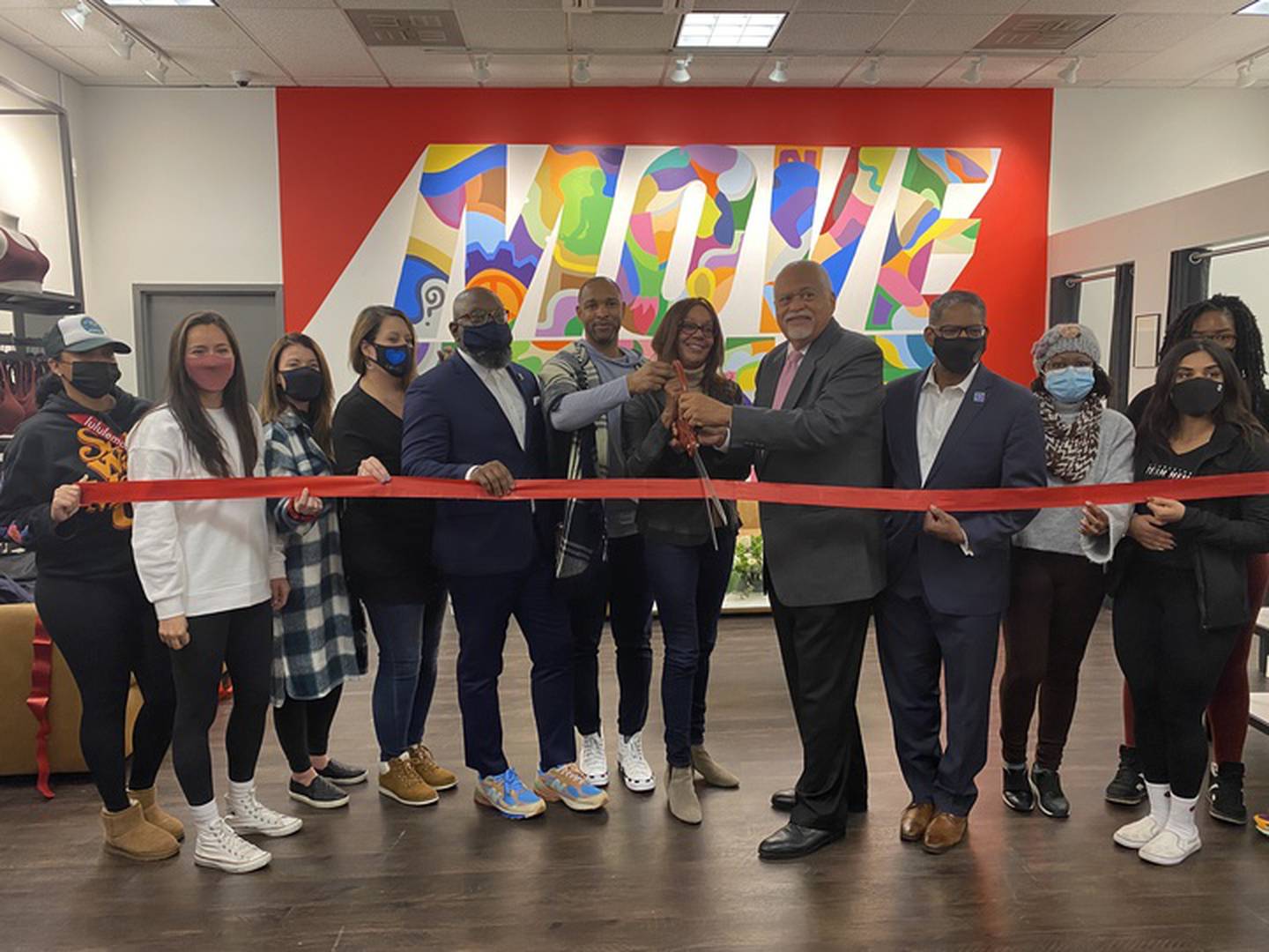 Lululemon Hyde Park store employees, including general manager Michael "Muffy" Collins (center) pose for a ribbon cutting alongside Hyde Park city's chamber of commerce members.