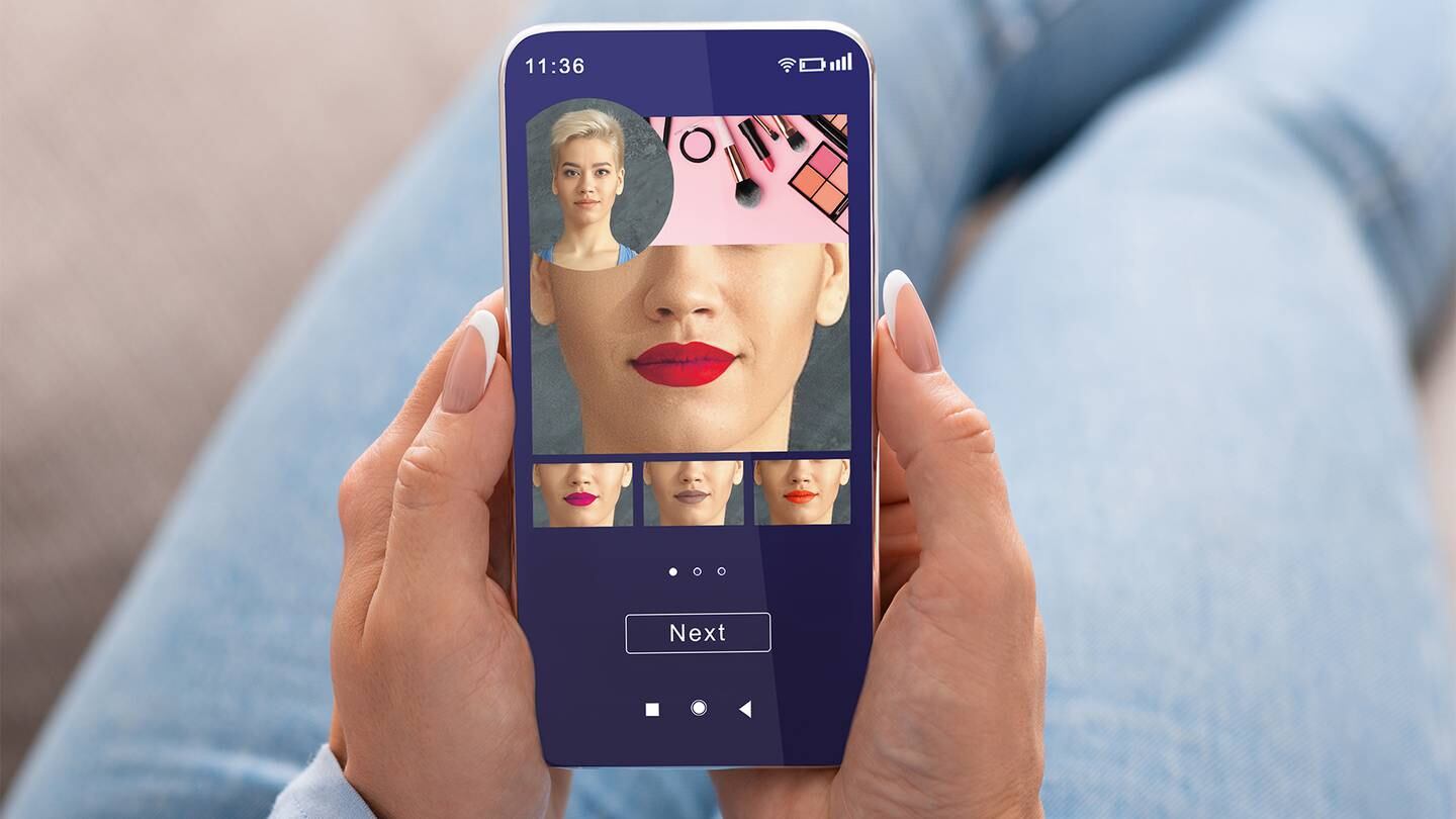 A person holds their mobile phone with the screen showing different lipstick colours on a virtual beauty app.