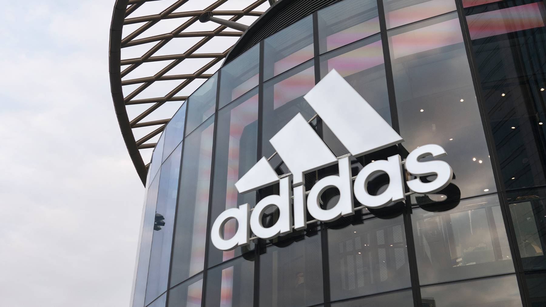 A shot of the Adidas logo on a glass storefront.